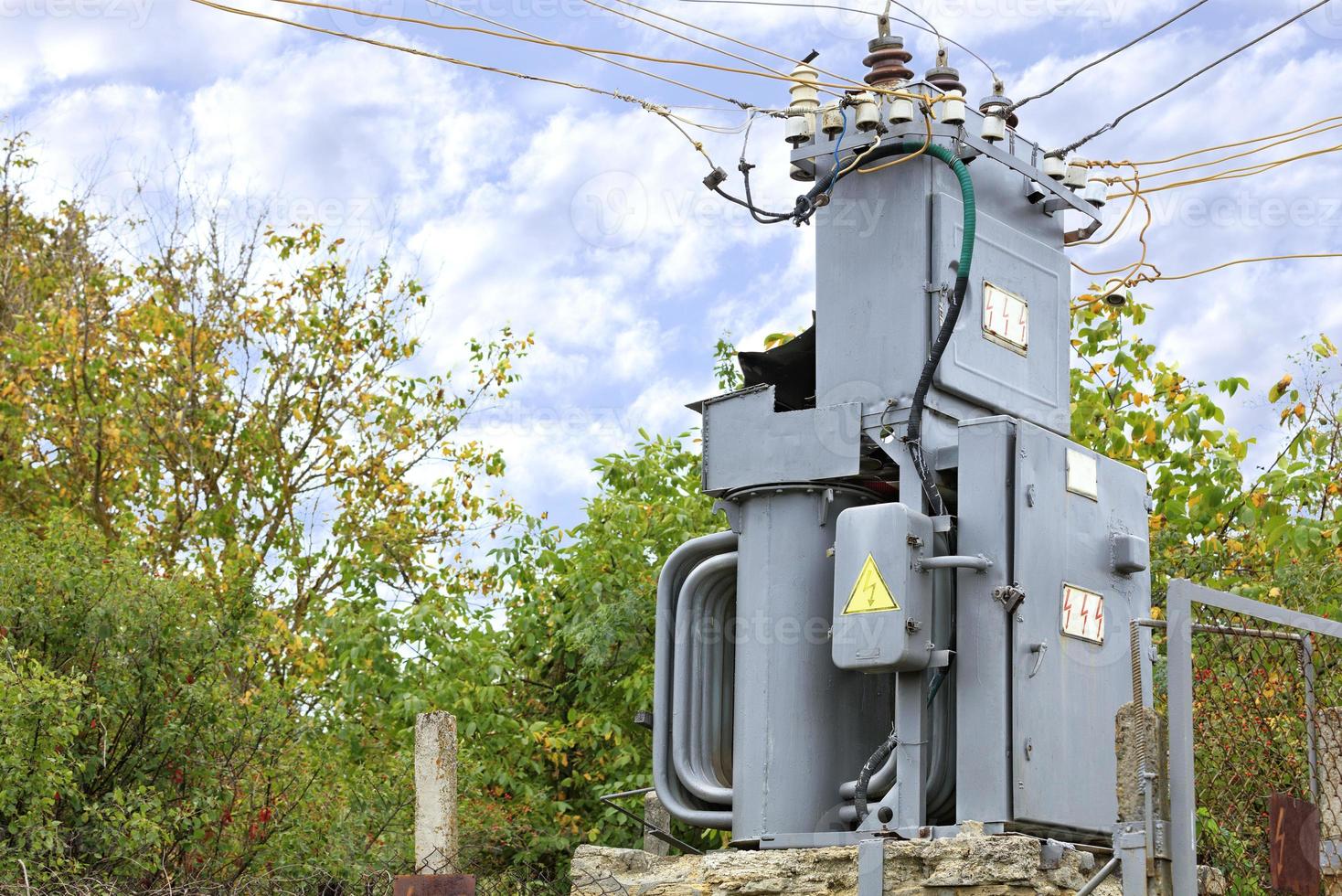 Transformer substation stands in the middle of the garden against a blue cloudy sky. photo