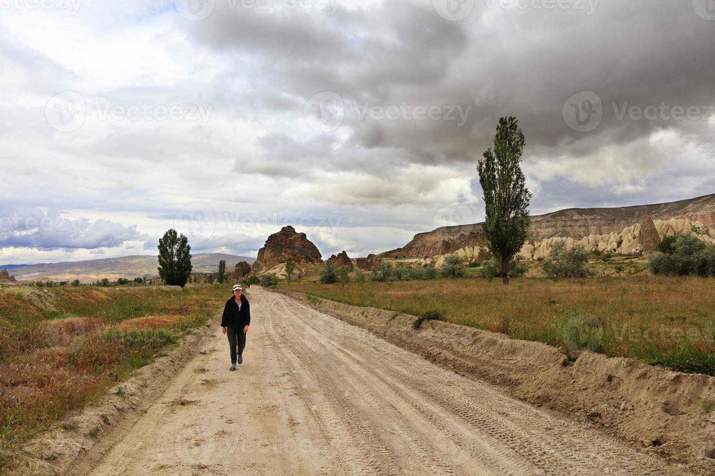 Tourist woman returns home on a dirt sandy road. photo