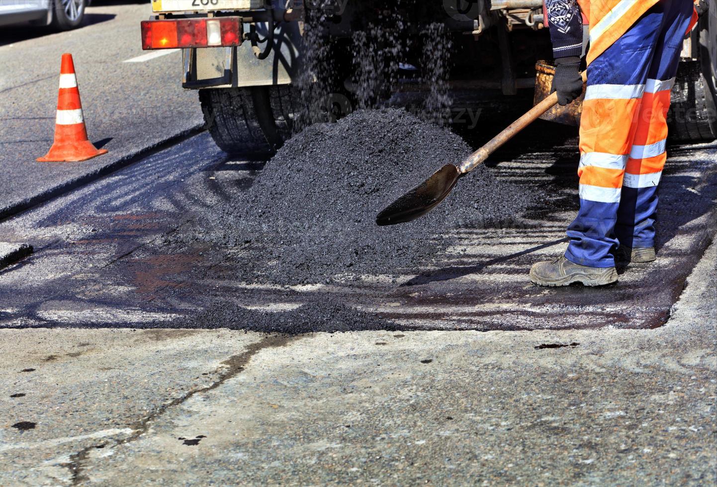 el constructor de carreteras vierte asfalto fresco y renueva una parte de la carretera para su reparación. foto