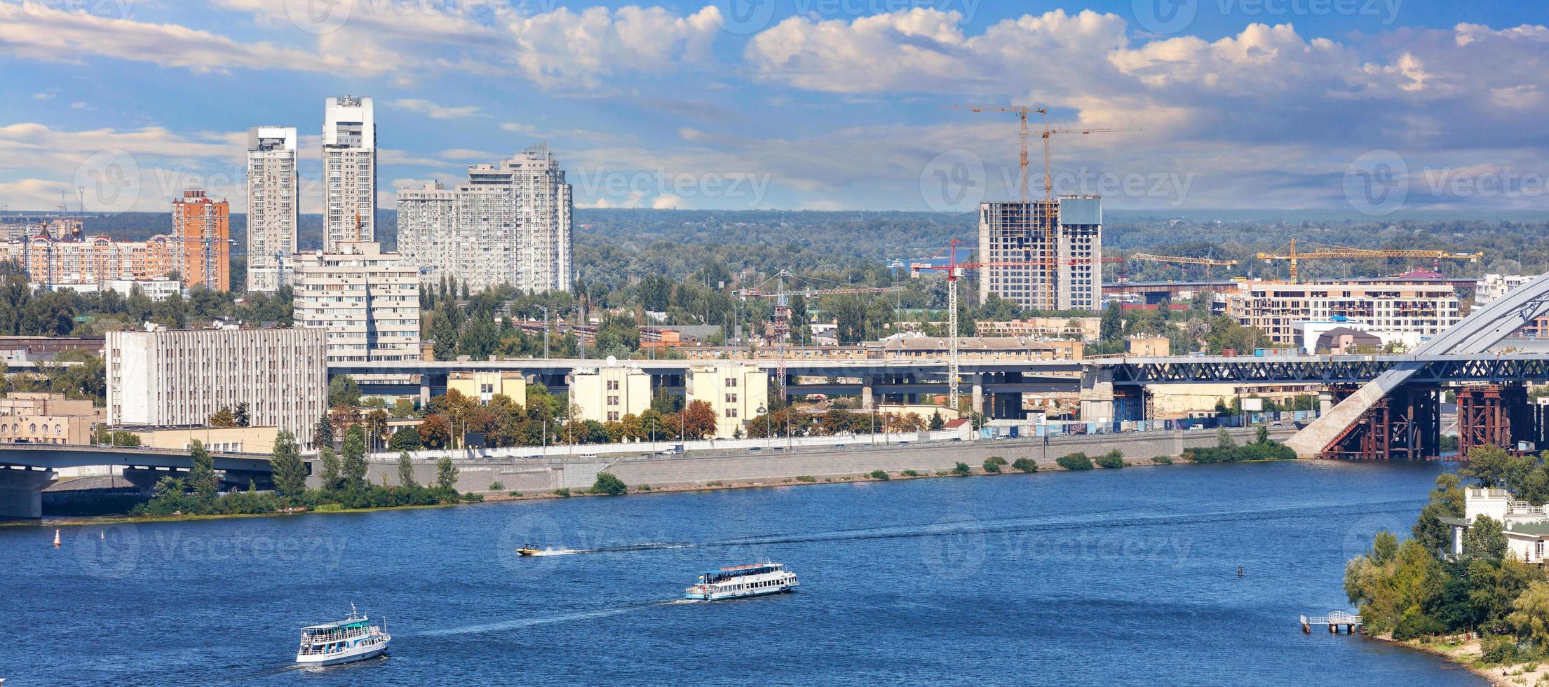 paisaje panorámico del dnipro con cruceros de recreo en el contexto del terraplén de kyiv, el hermoso cielo brillante y los edificios de la ciudad. foto