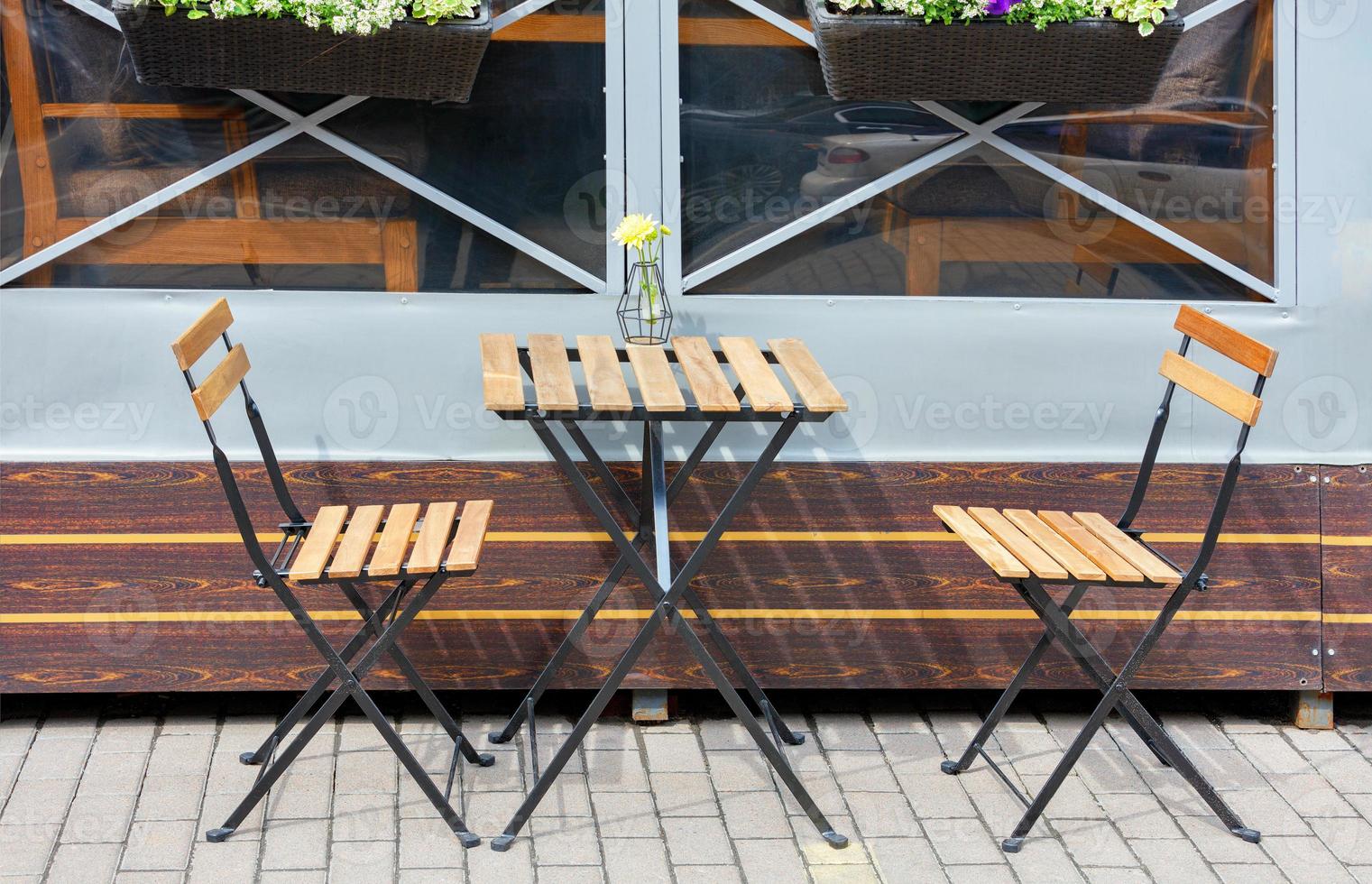 Área de café al aire libre, muebles de jardín, mesa y sillas plegables en la acera. foto