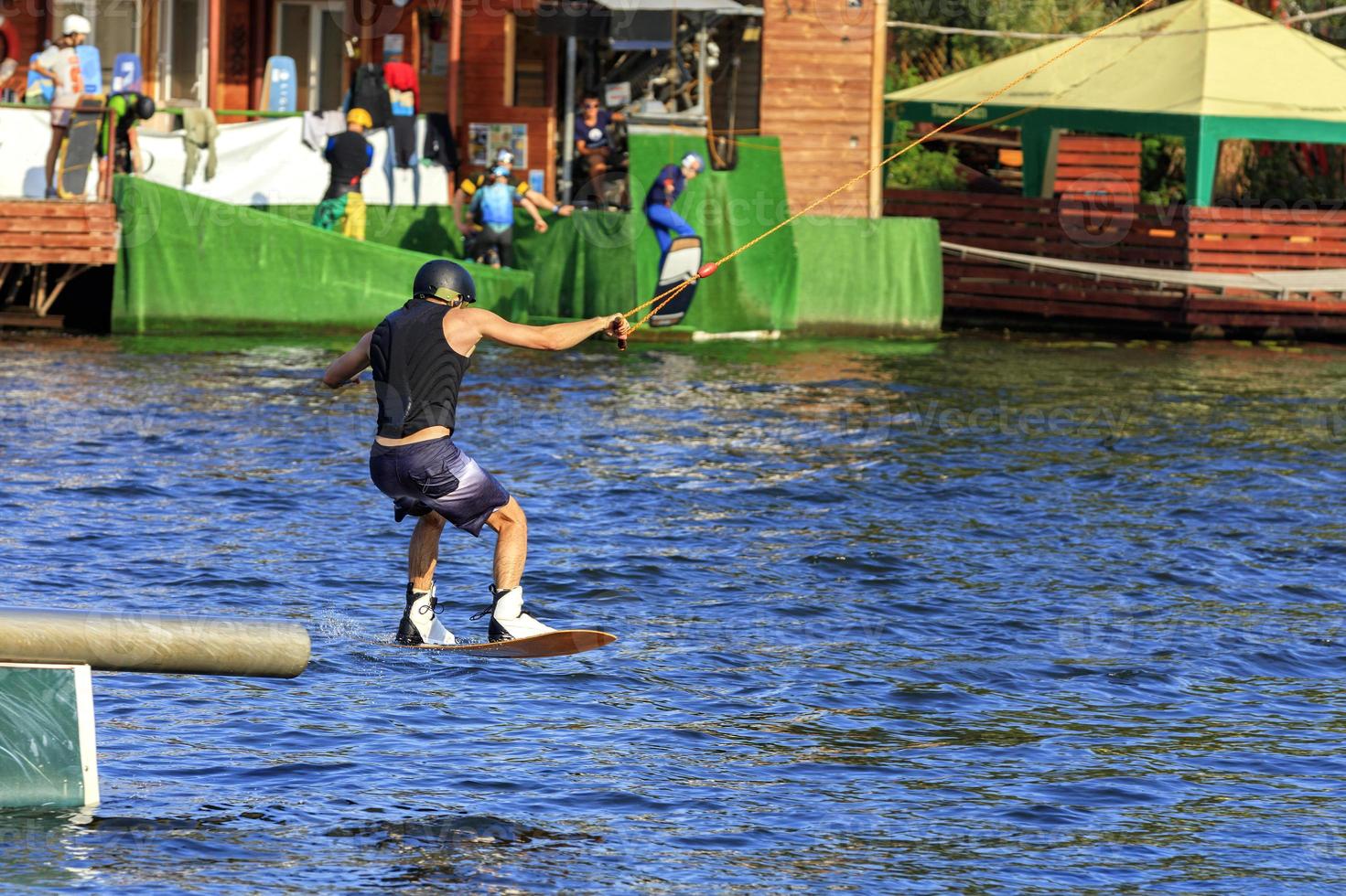 A wakeboarder rushes through the water at high speed overcoming various obstacles. photo