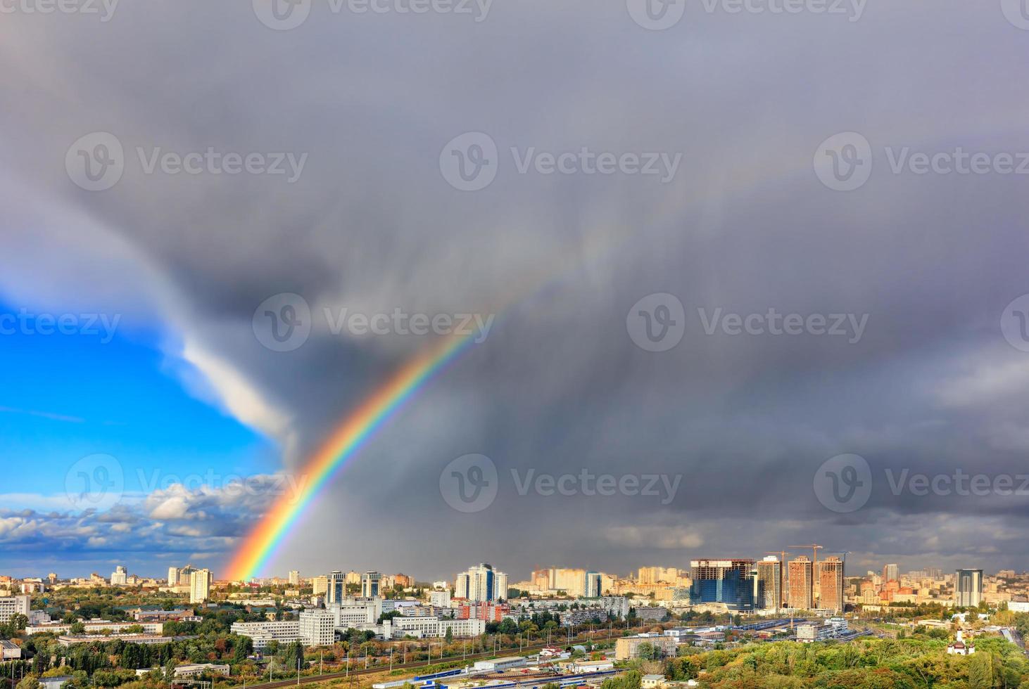 A bright rainbow in the sky above city houses after a thunderstorm separates thunderclouds from the clear sky. photo