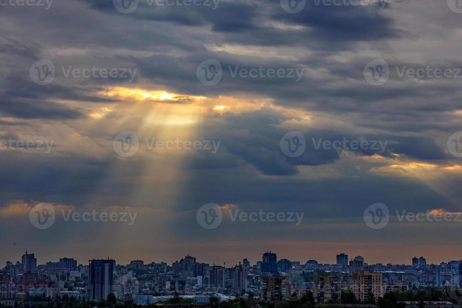 The sun's rays break through dense clouds at dawn over the city. photo