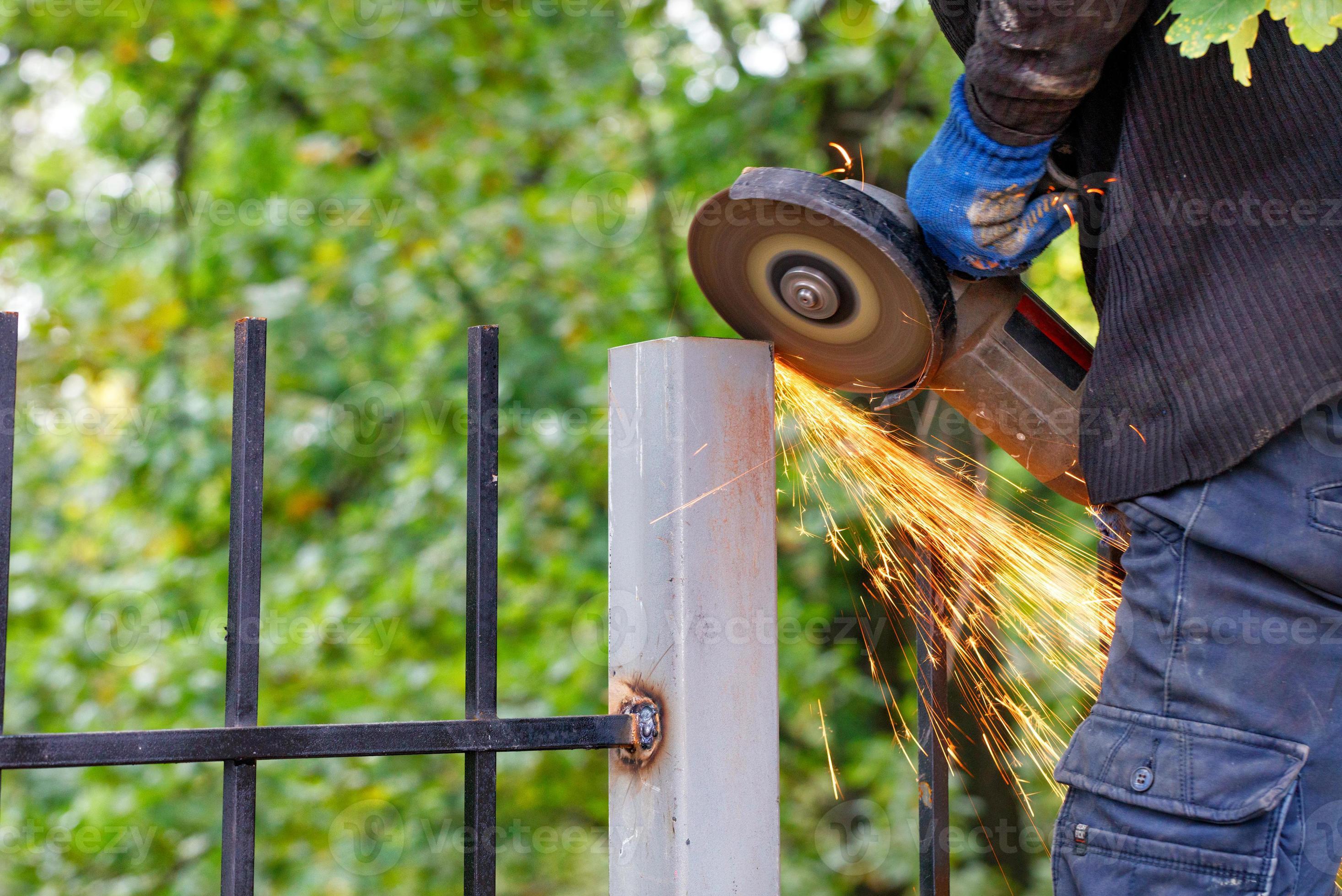 A worker uses a disc angle grinder to trim a metal post. 4708385 Stock Photo at Vecteezy