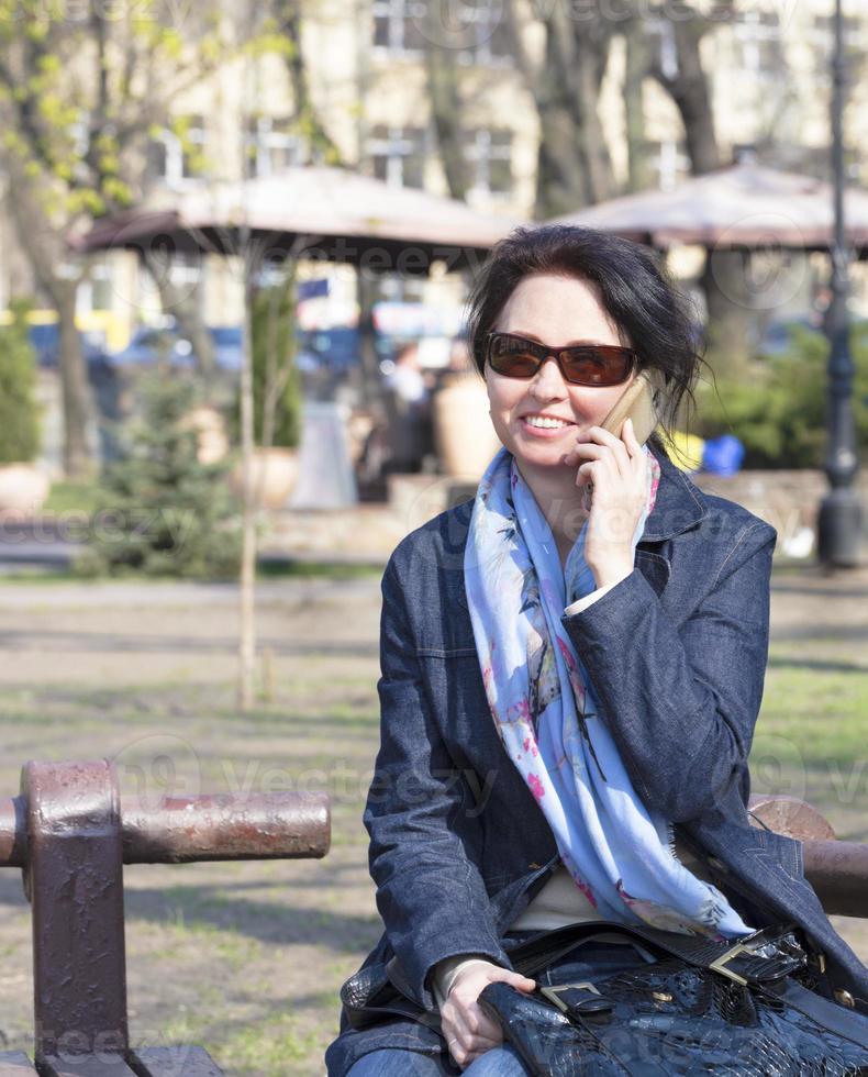 A young woman with a joyful mood communicates on a smartphone in a spring park photo