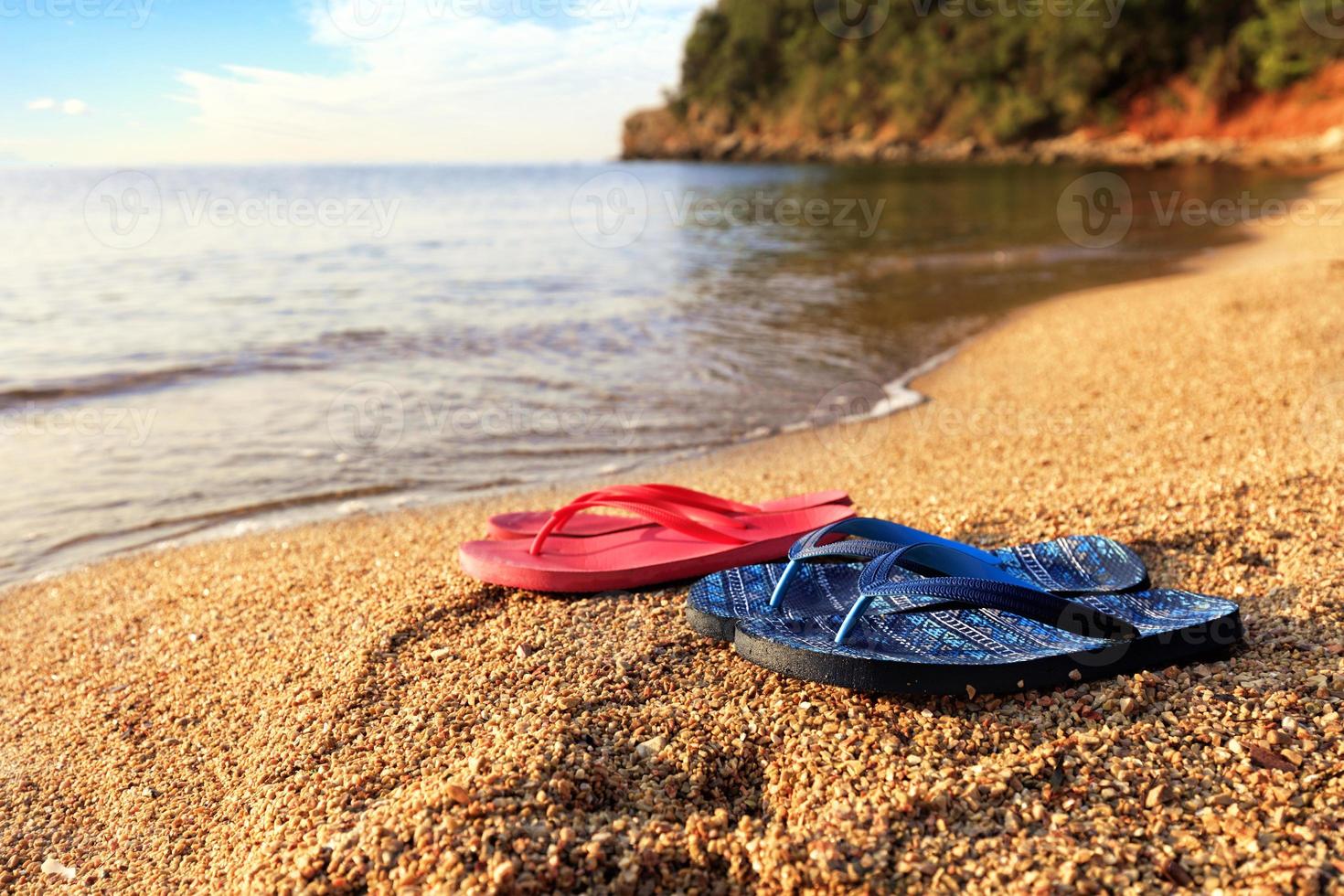 zapatillas de playa se encuentran en una piedra cerca del mar transparente foto