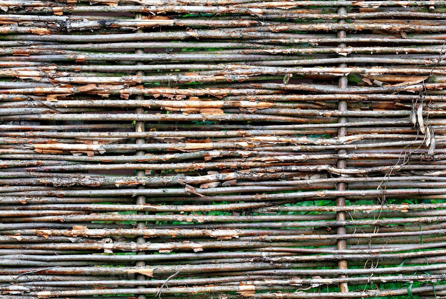 Fragment of a wicker fence made of old branches close-up in bright sunlight. photo