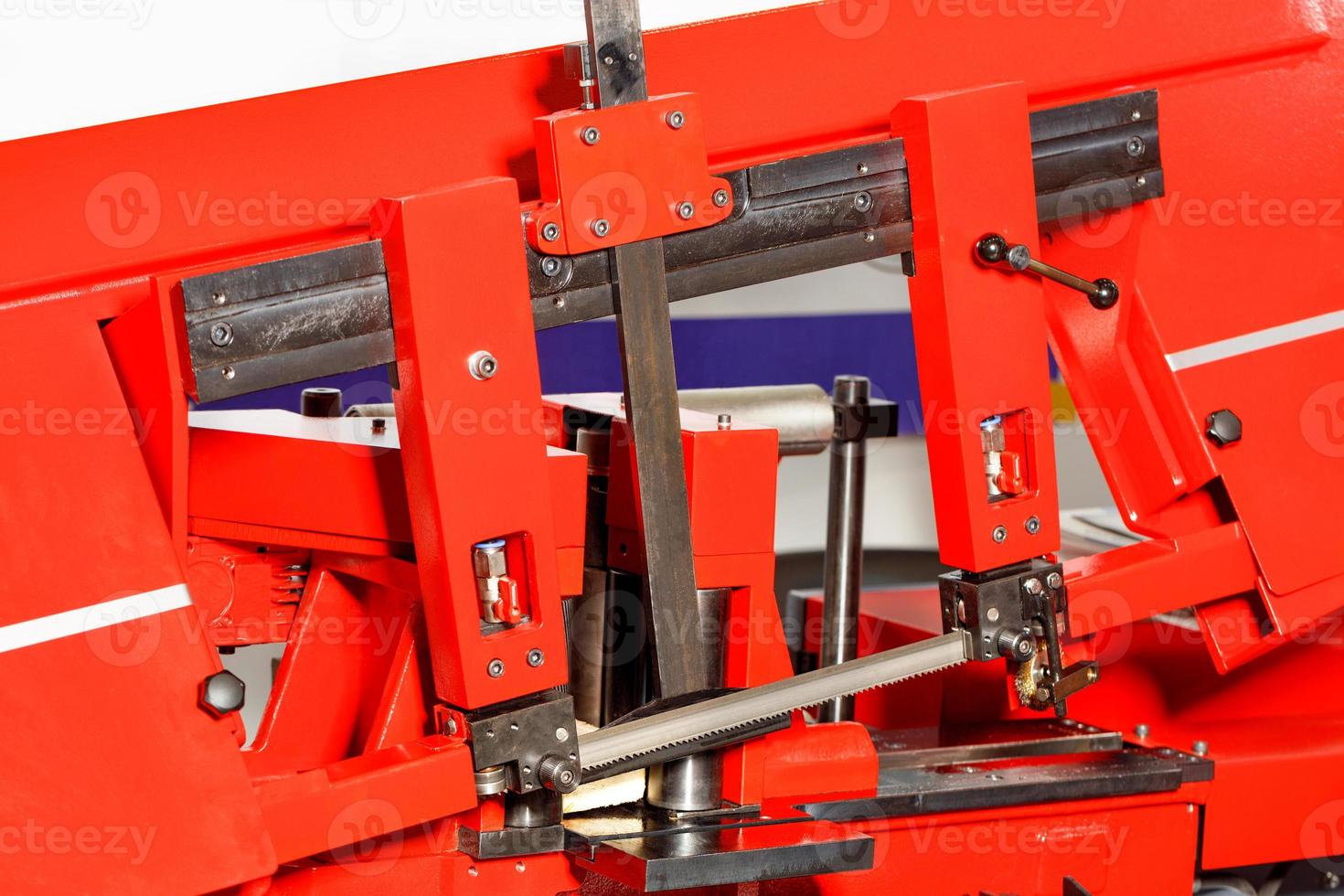 Sharp teeth of a band saw with a ruler on a modern red metalworking machine, close-up. photo