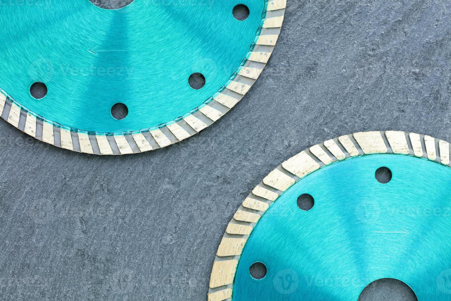 Part of the diamond cutting wheels of emerald color against the background of gray granite. photo