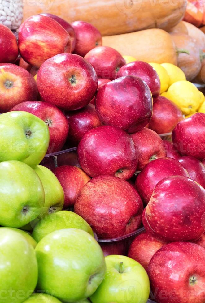 Red and green apples are stacked in a heap on the market counter and attract the attention of buyers. photo