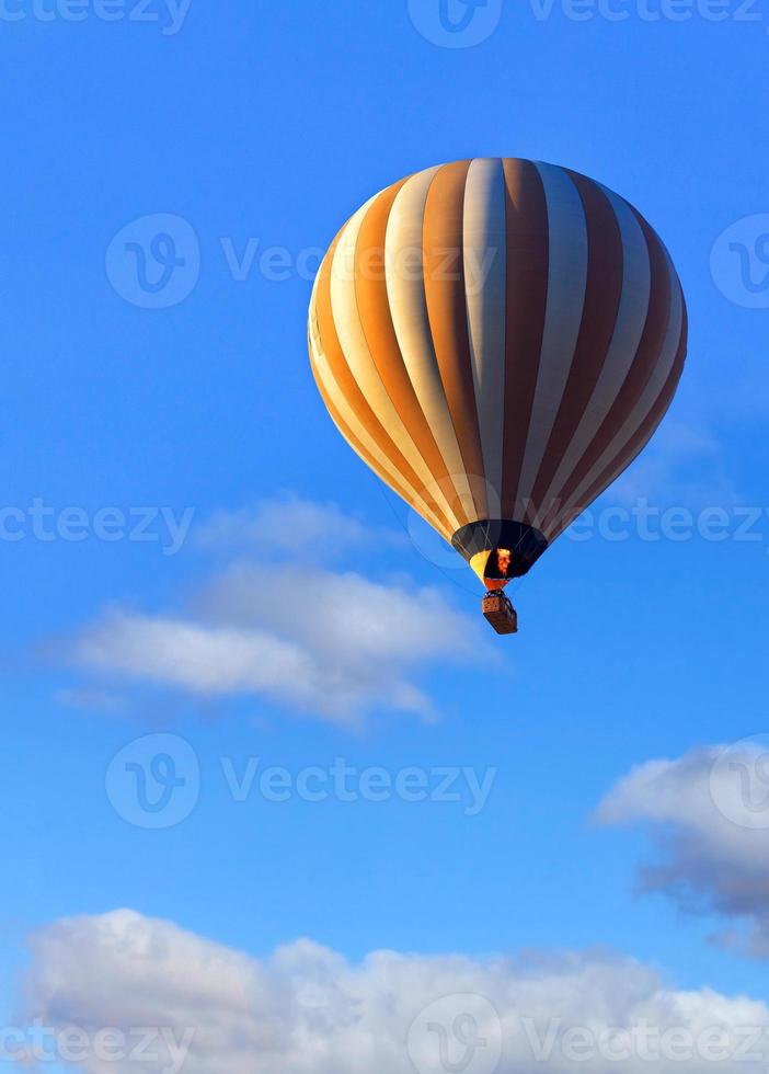 Flying beautiful hot air balloon with a basket of tourists in the blue sky. Close-up, copy space. photo