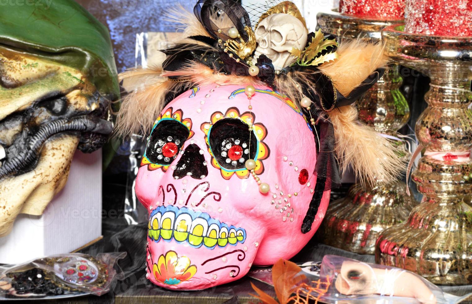 Halloween, pink skull doll with female makeup and a hat with feathers isolated on a blurred background. photo