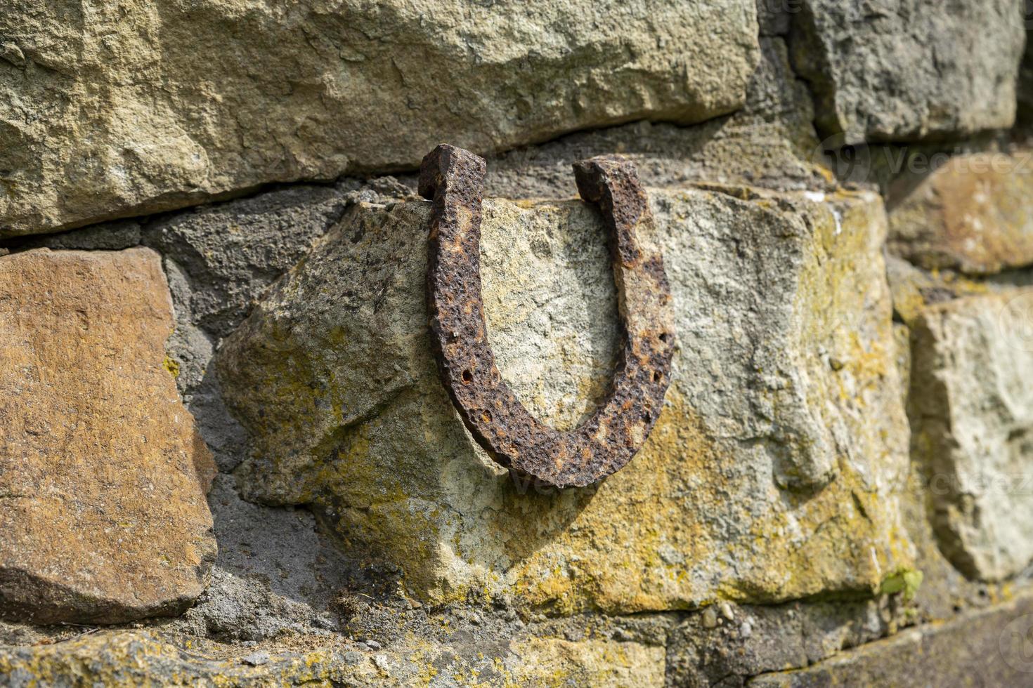 Close-up of an old rusty horseshoe propped on a big stone. photo