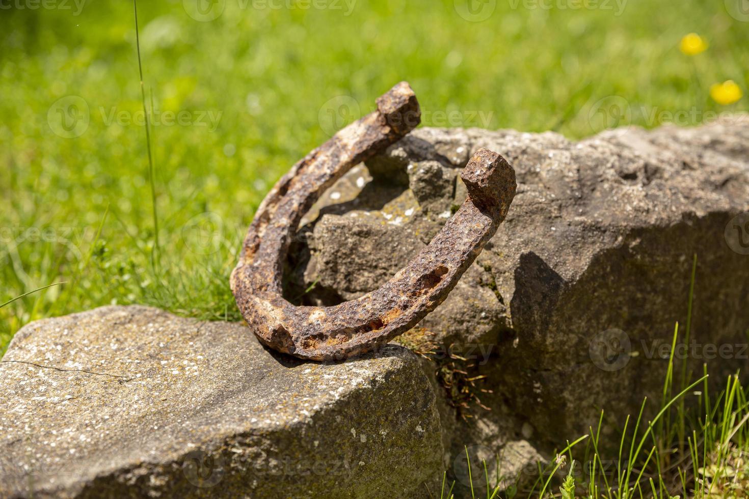Close-up of an old rusty horseshoe propped on a big stone. photo