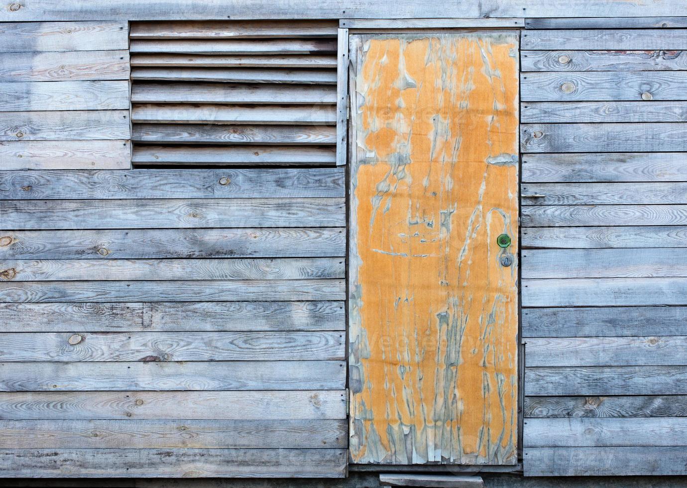 Antiguo granero de madera curtida por la intemperie con una vieja puerta amarilla foto