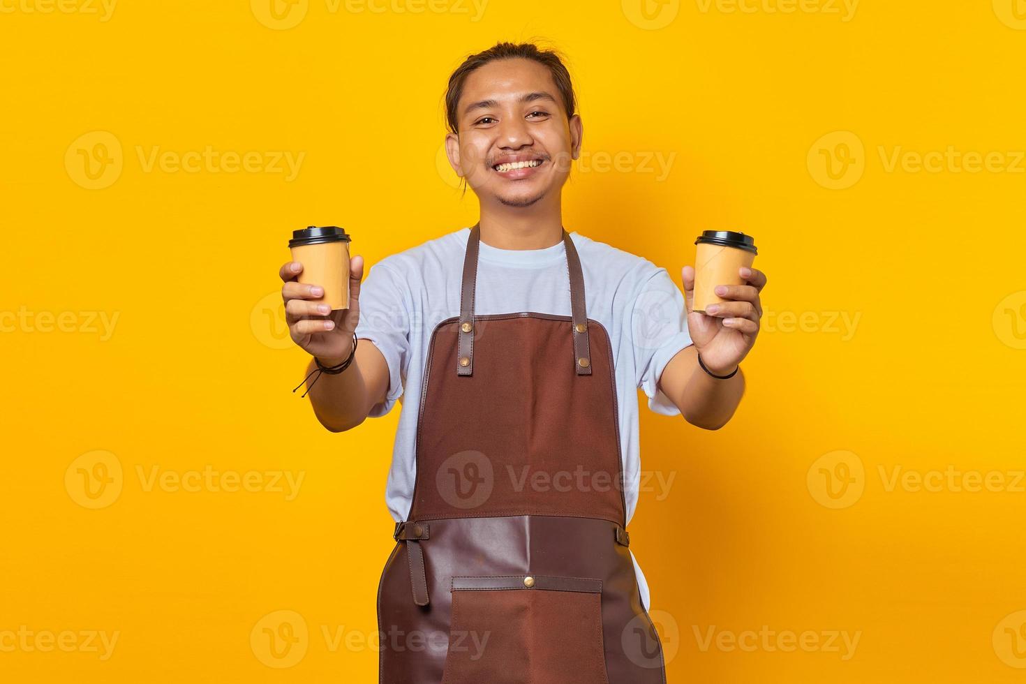 retrato, de, alegre, barista, hombre, tenencia, dos, papel, tazas de café, para elegir, aislado, en, fondo amarillo foto