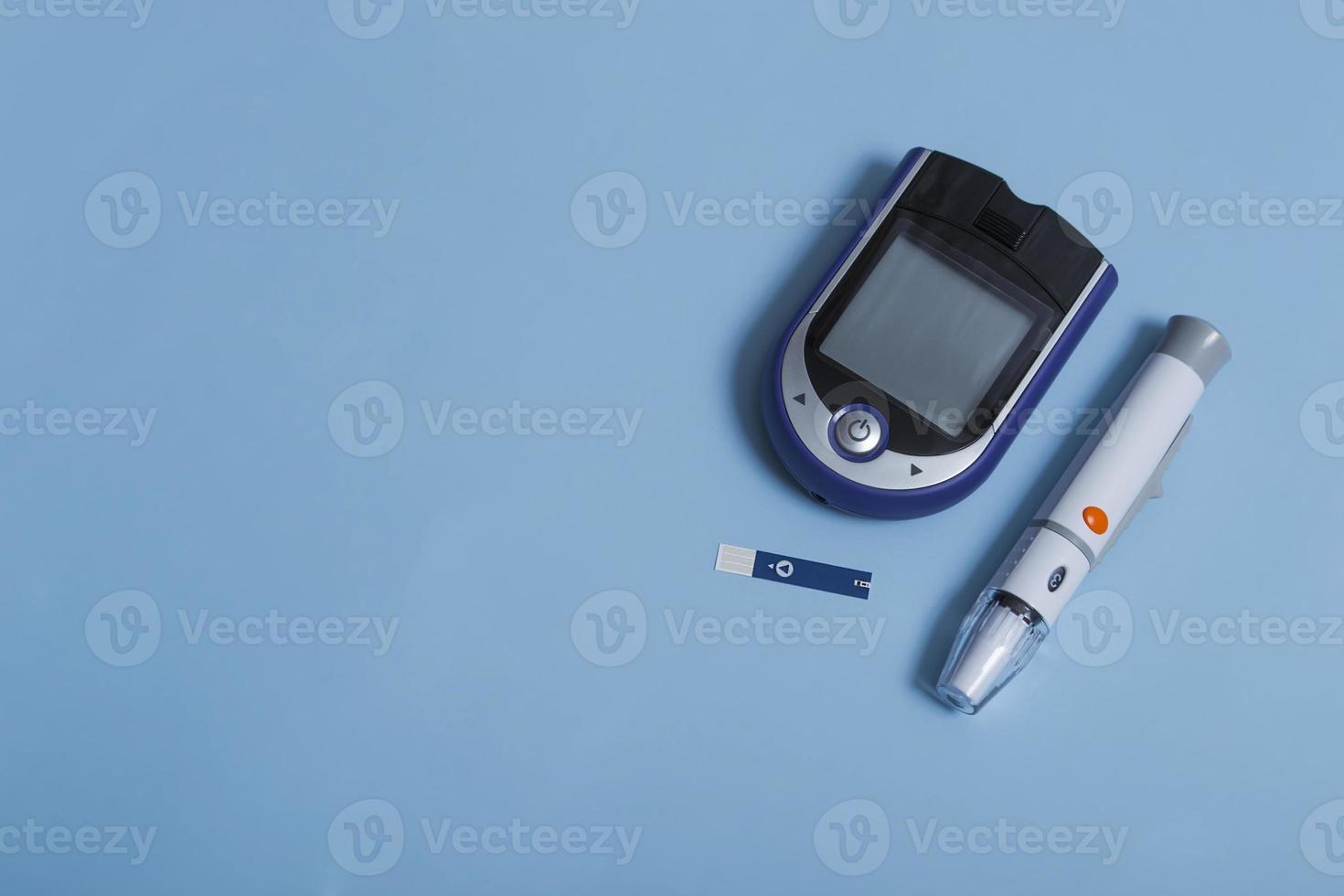 Blood glucose meter, test strips and syringe for monitoring diabetes mellitus with copy space isolated on color background. photo