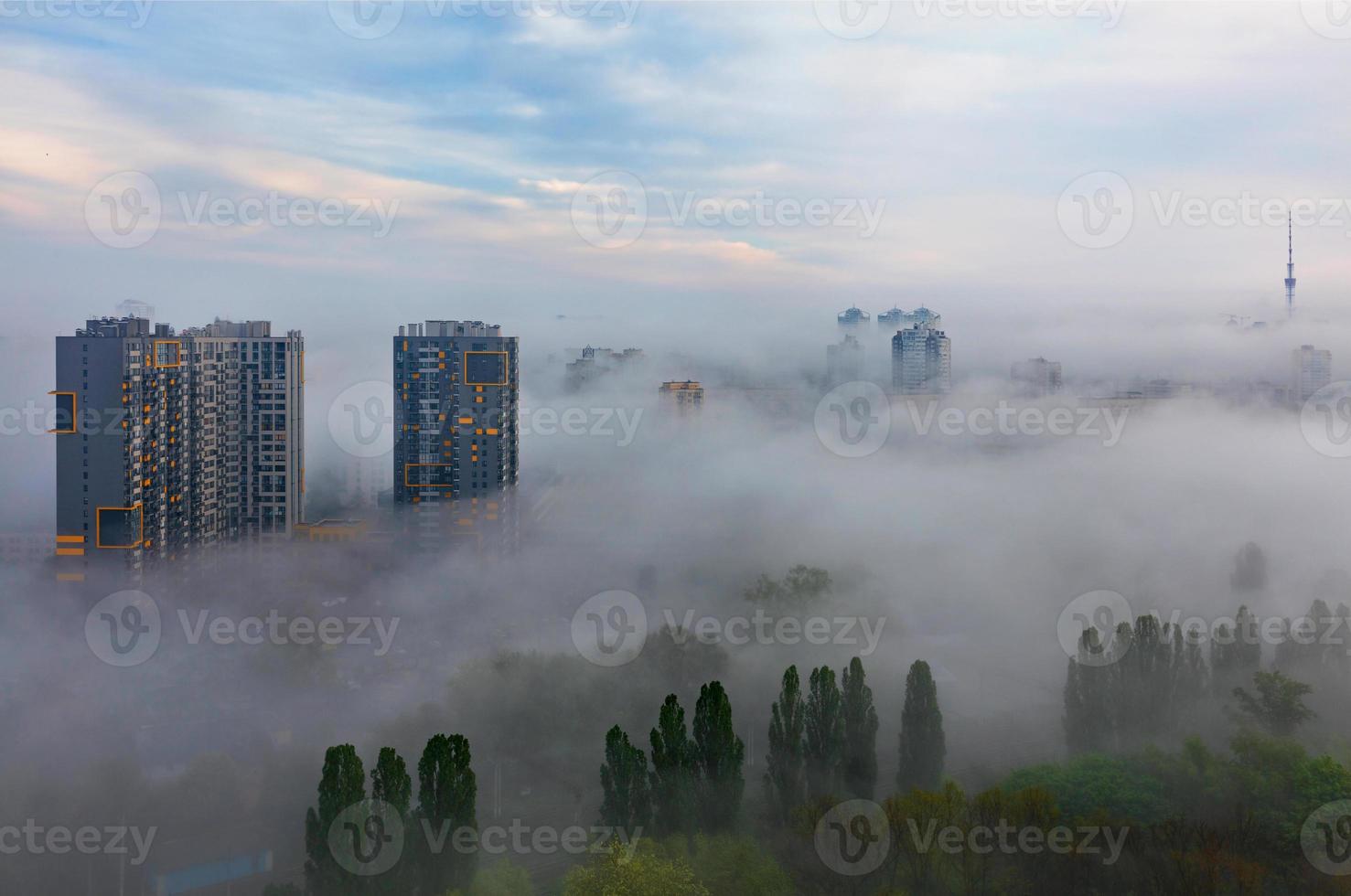 A thick fog descended in the early morning on the sleeping city and stretches between residential high-rise buildings and over the green park. photo