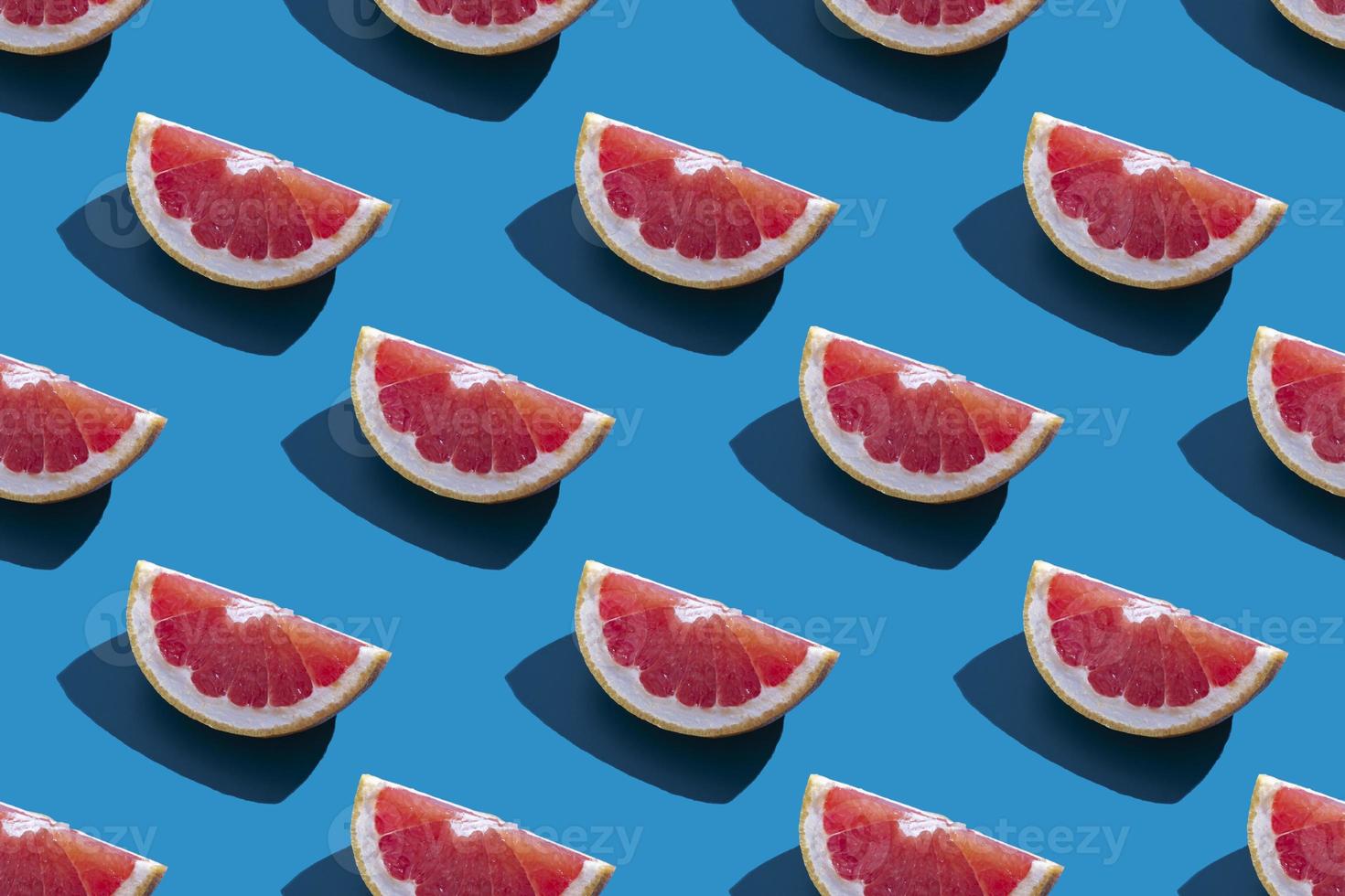 Seamless pattern of orange grapefruit with shadow on a blue background. Minimal trendy summer vacation concept. Healthy eating lifestyle. photo