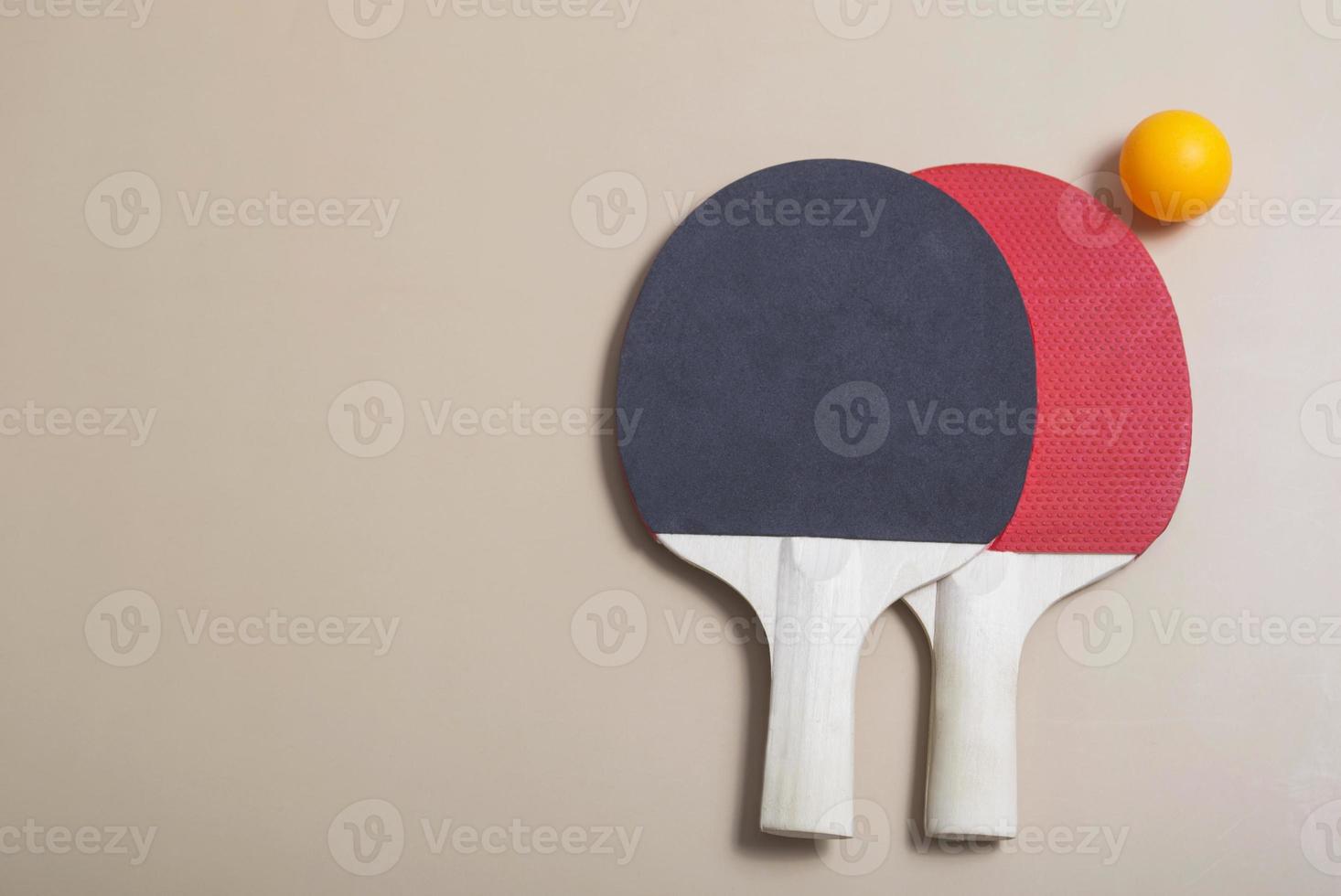 dos raquetas de tenis y pelotas de color naranja y blanco sobre un fondo beige. recreación deportiva raquetas de ping pong. bandera foto