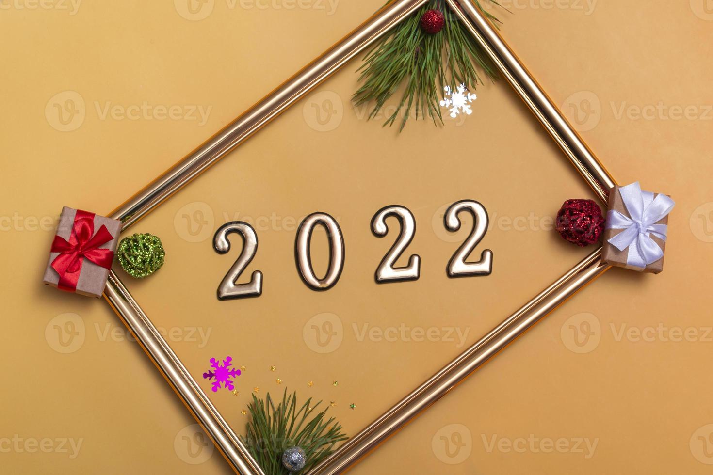 New Year's layout on a beige background Christmas balls, branches of a Christmas tree, a gift box and a gold frame, a mockup of a postcard, an invitation photo