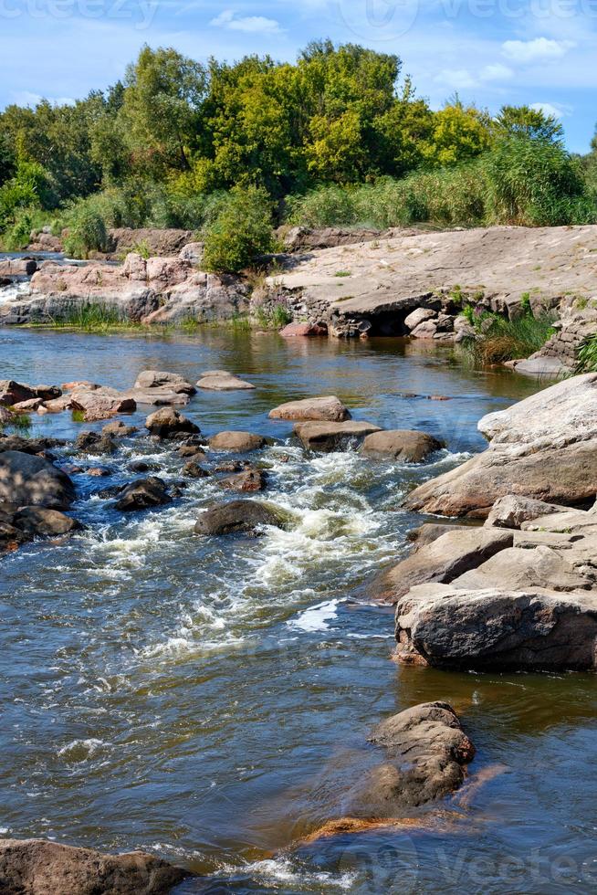 una corriente rápida de agua de un río de montaña corre a través de rápidos de piedra en un día de verano. imagen vertical. foto