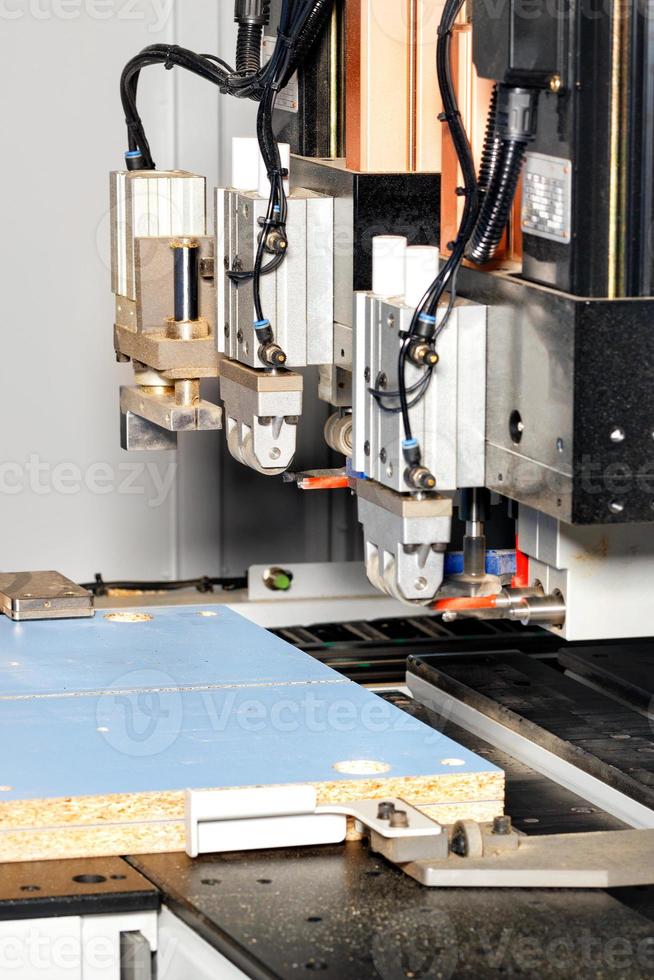 The process of manufacturing cabinet furniture from chipboard on a modern automatic drilling and milling machine, selective focus. photo