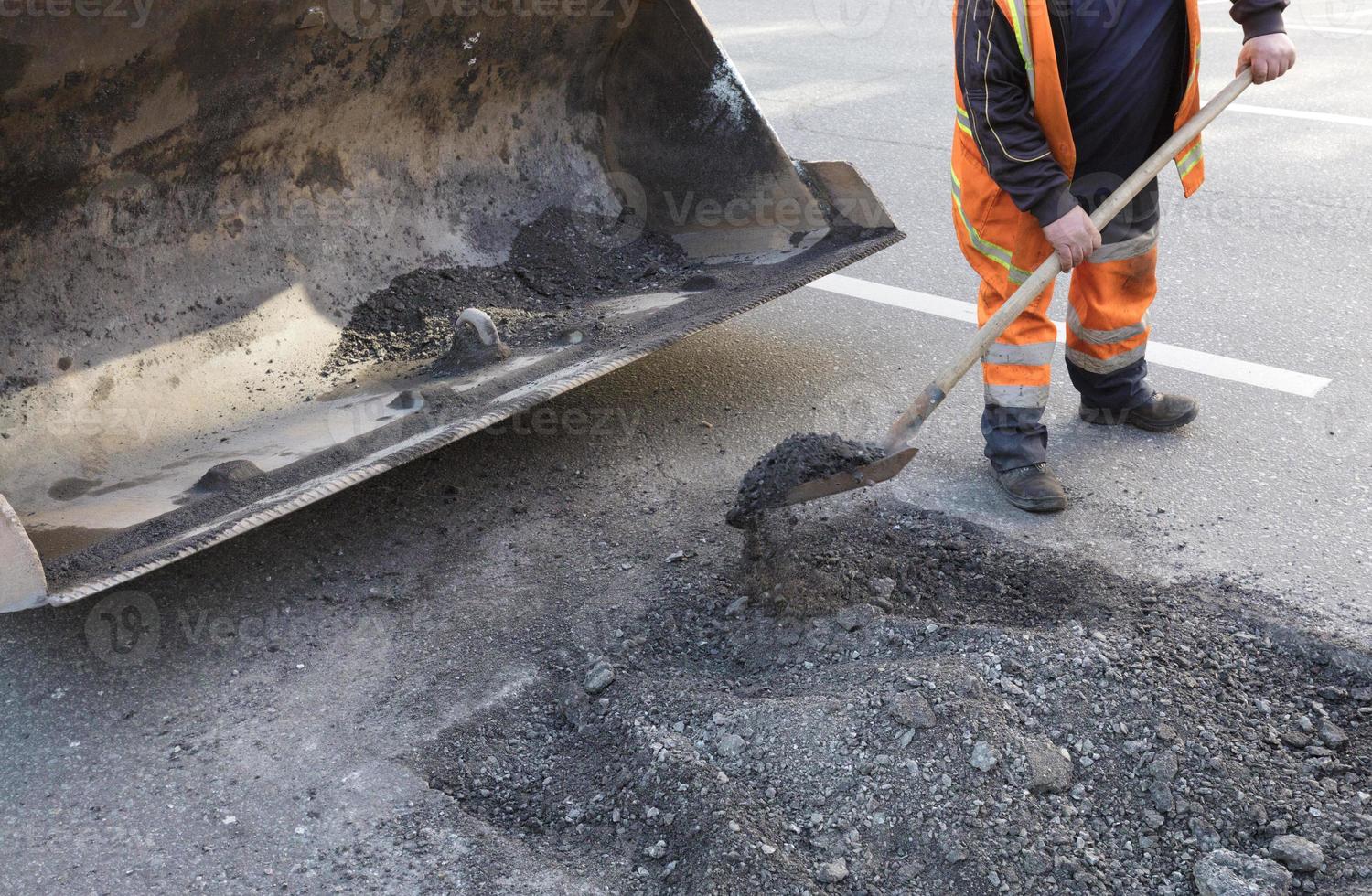 reparación parcial de la carretera asfaltada. el trabajador limpia una parte mala de la carretera foto