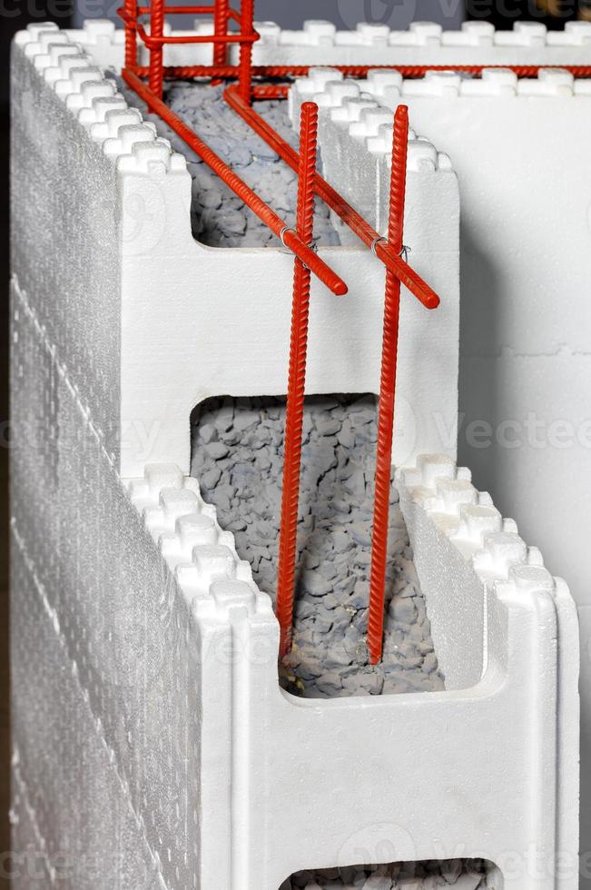 utilizando refuerzo metálico junto con hormigón en mampostería para reforzar y aislar paredes de poliestireno y espuma de poliuretano. imagen vertical. foto