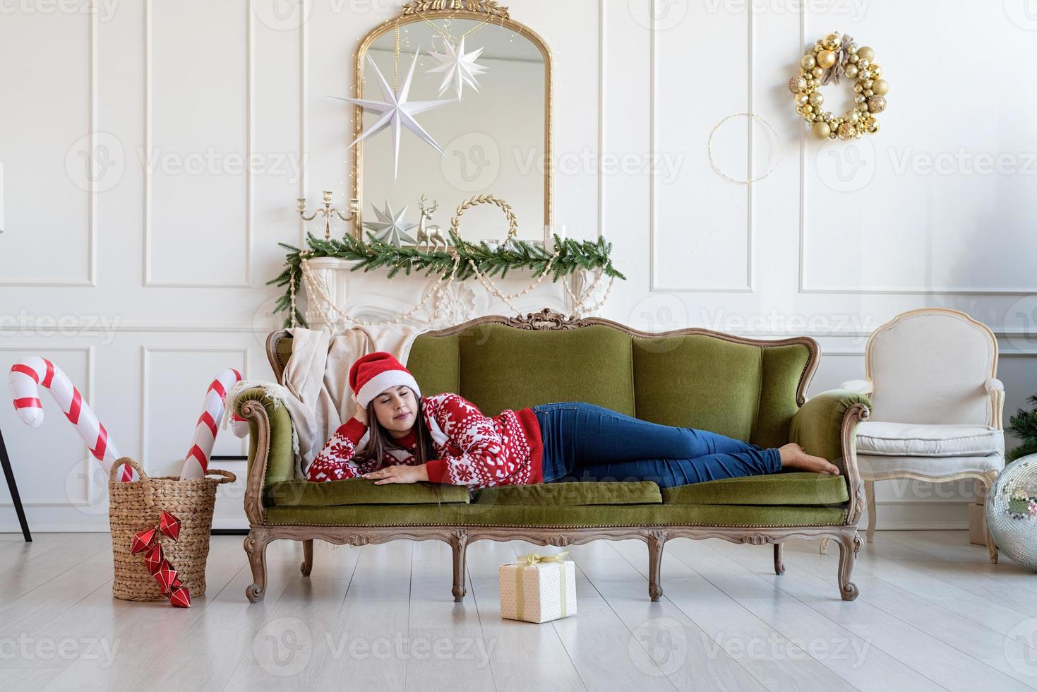 Young woman lying on couch alone in a decorated for Christmas living room photo
