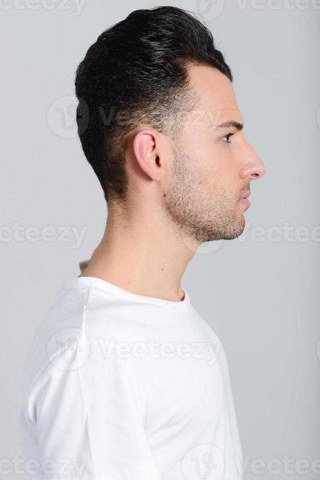 Serious young man standing against white background photo