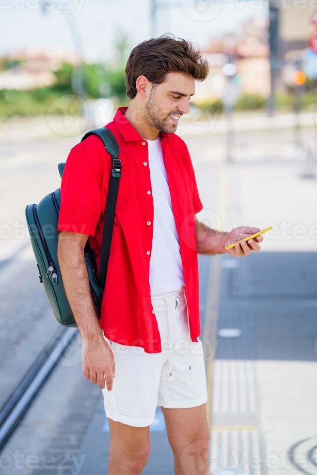 Young man waiting for a train at an outside station photo