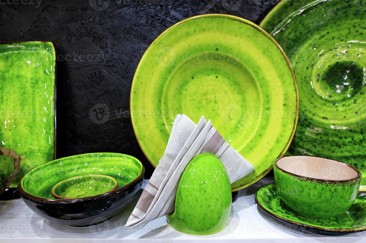 A flannel napkin and set of pottery covered with bright green glaze. photo