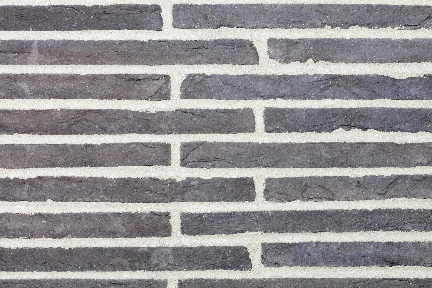 Texture of dark gray horizontal stone slabs embedded in the wall. photo