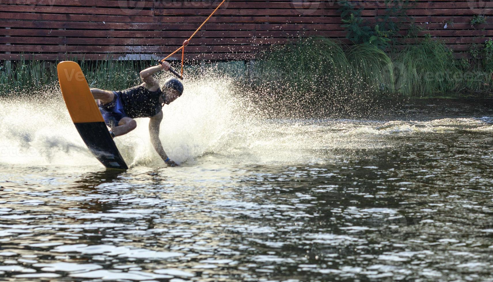 A wakeboarder rushes through the water at high speed raising a column of water at a sharp turn. photo