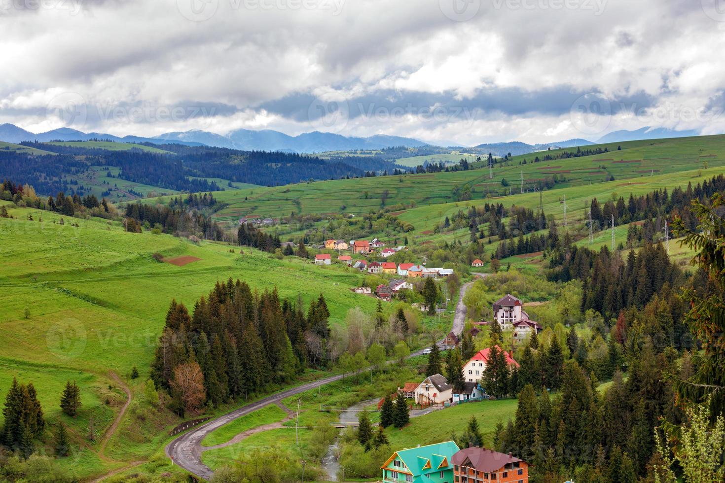 A picturesque landscape of a Carpathian village with a winding road and colorful roofs in early spring. photo