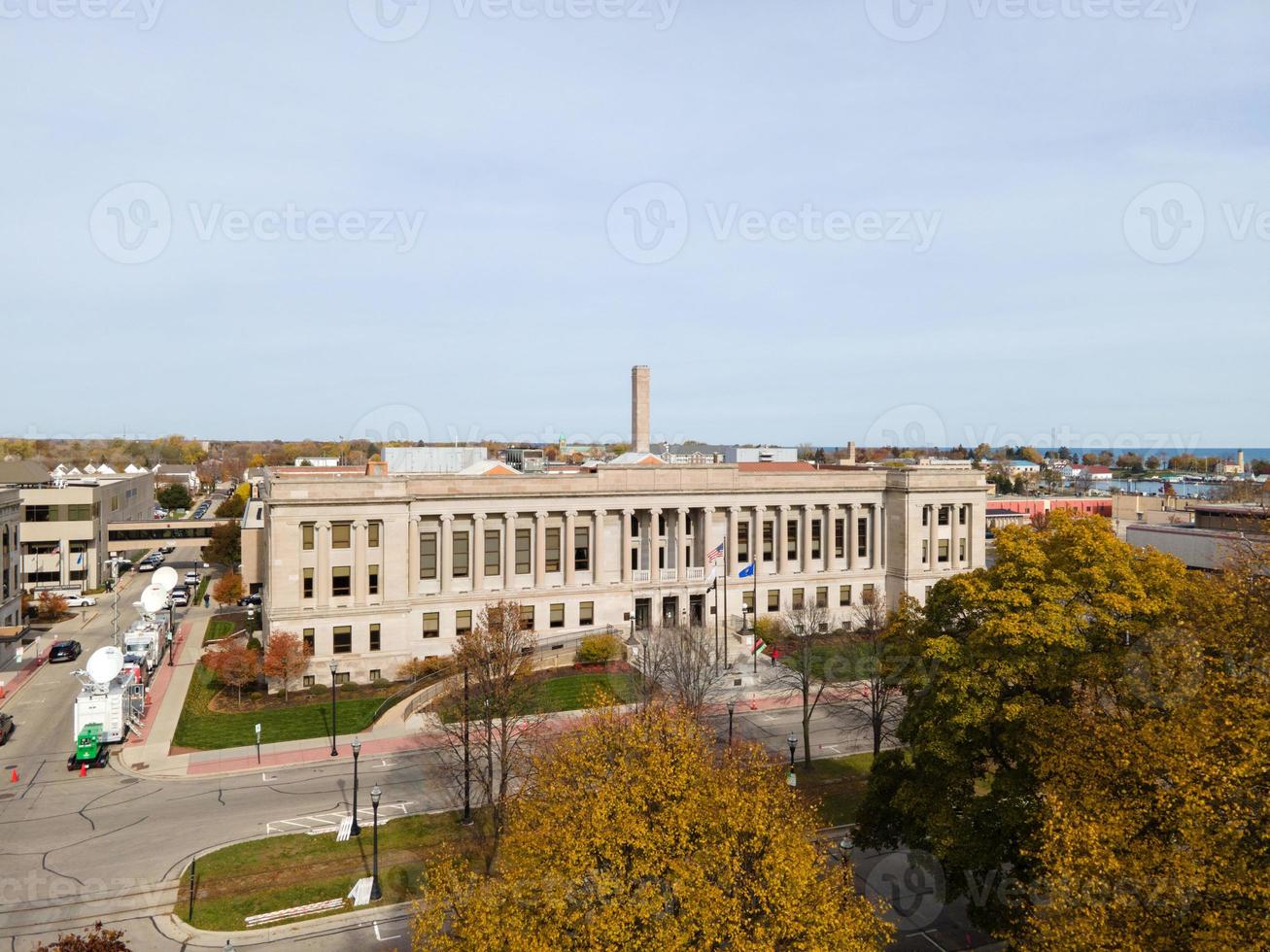 Kenosha County Court House on clear day with television broadcast vehicles present for trial coverage. Autumn colored trees present. photo