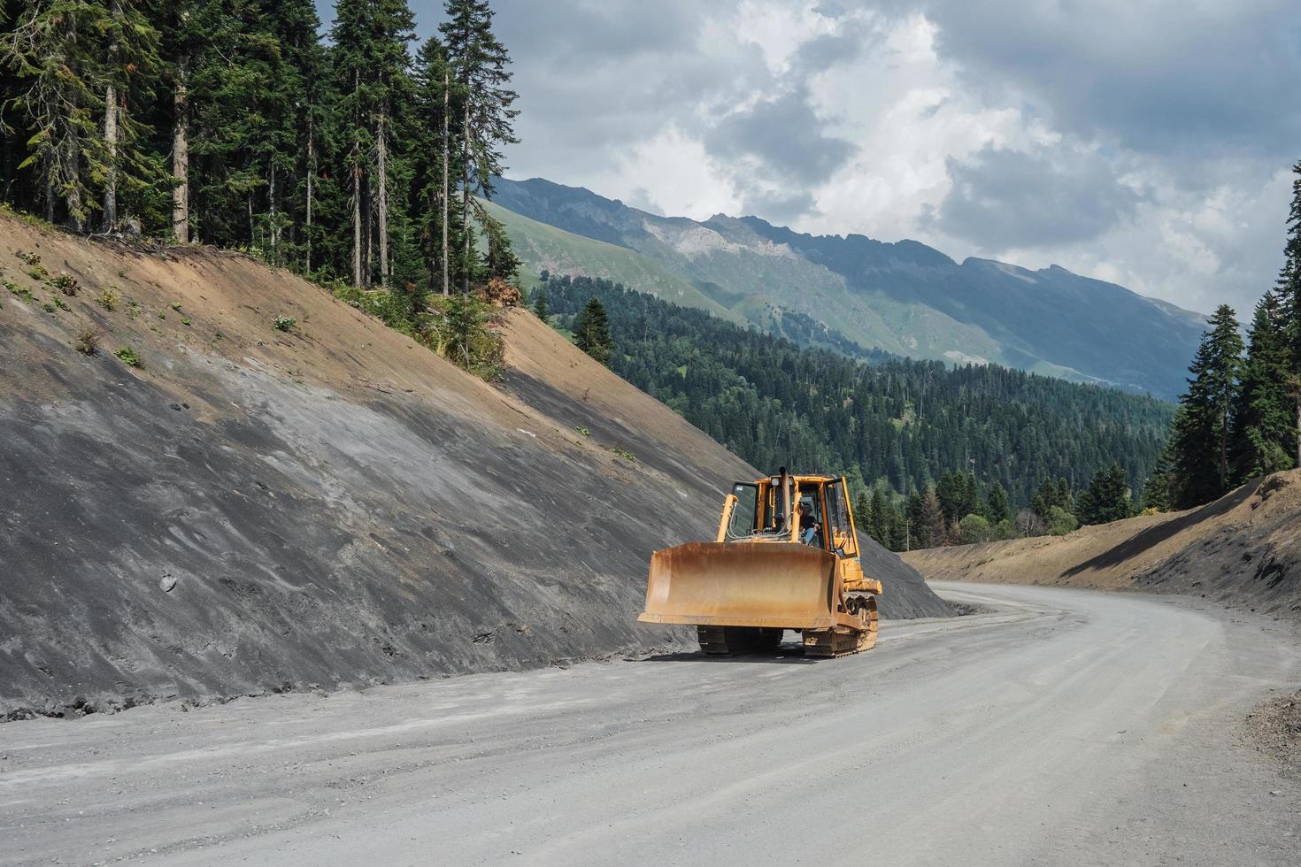 Crawler bulldozer driving on a dirt road in the mountains. photo