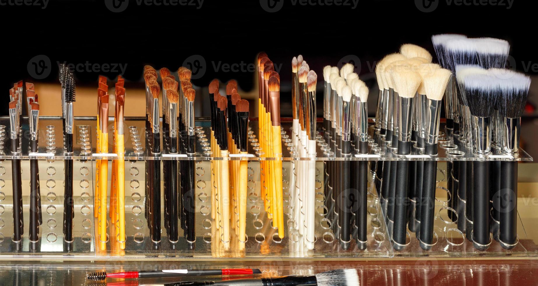 A set of makeup brushes in different sizes and shapes on a dark background. photo