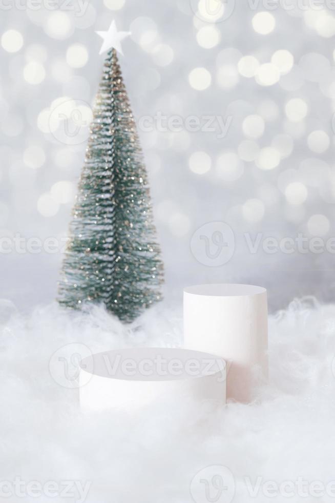 Podio o pedestal mok-up para cosméticos en la nieve con un árbol de Navidad en formato vertical de fondo bokeh foto