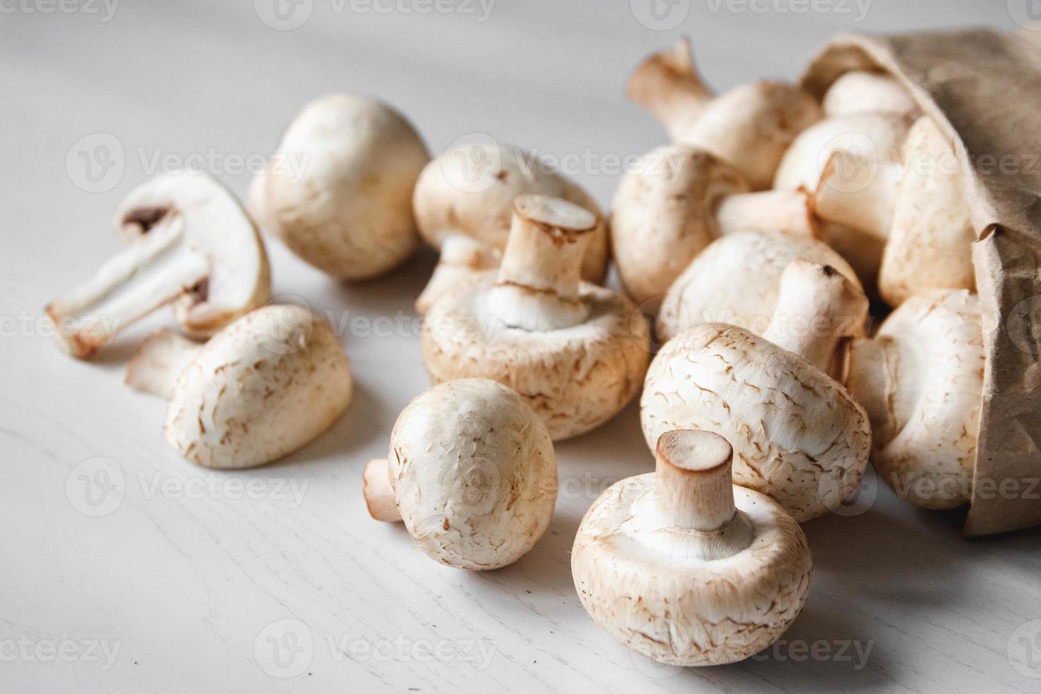 Mushrooms champignons in paper bag on a white wooden table photo