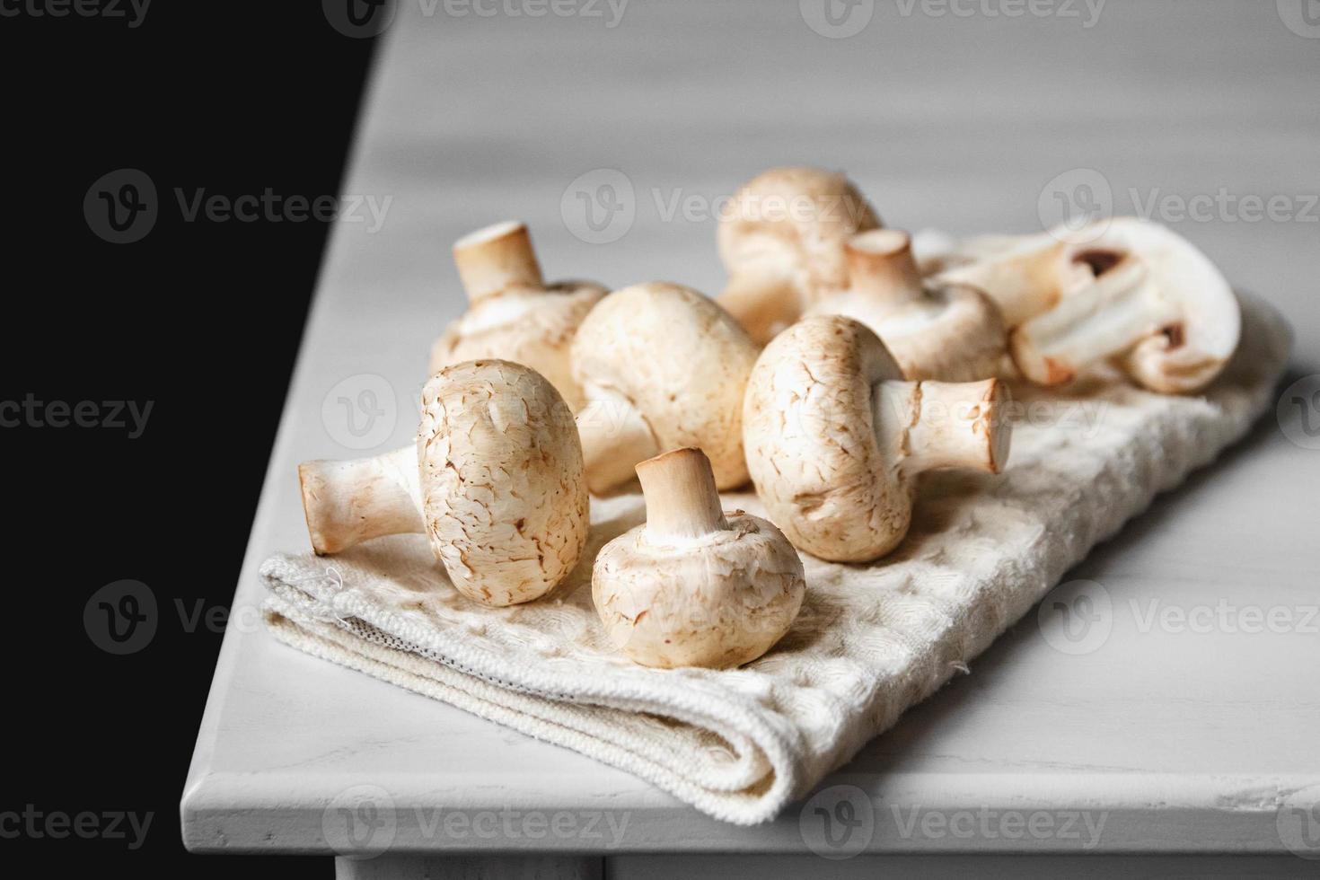 Mushrooms champignons on the kitchen napkin on a white wooden table photo