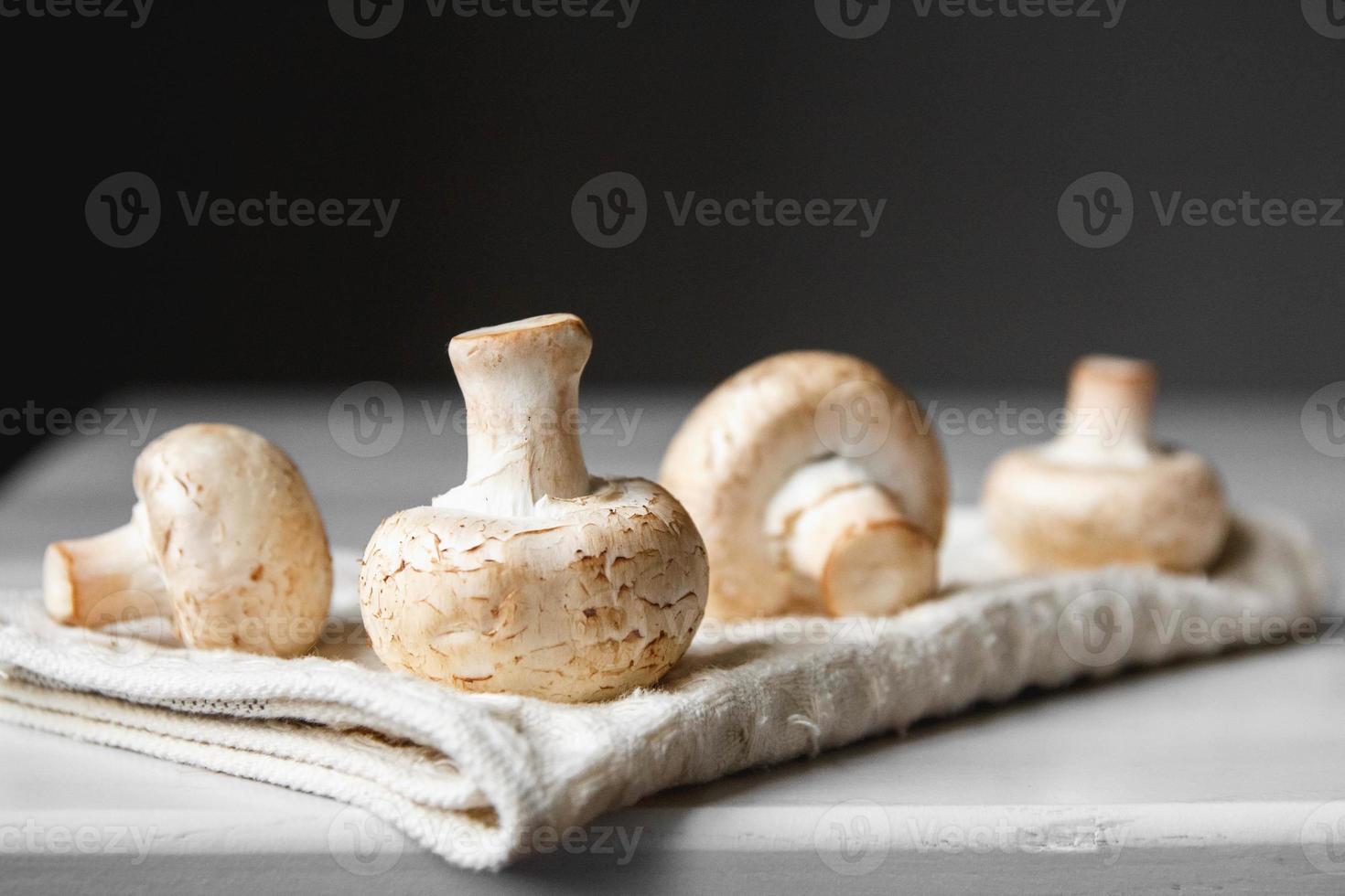 Mushrooms champignons on the kitchen napkin on a white wooden table photo