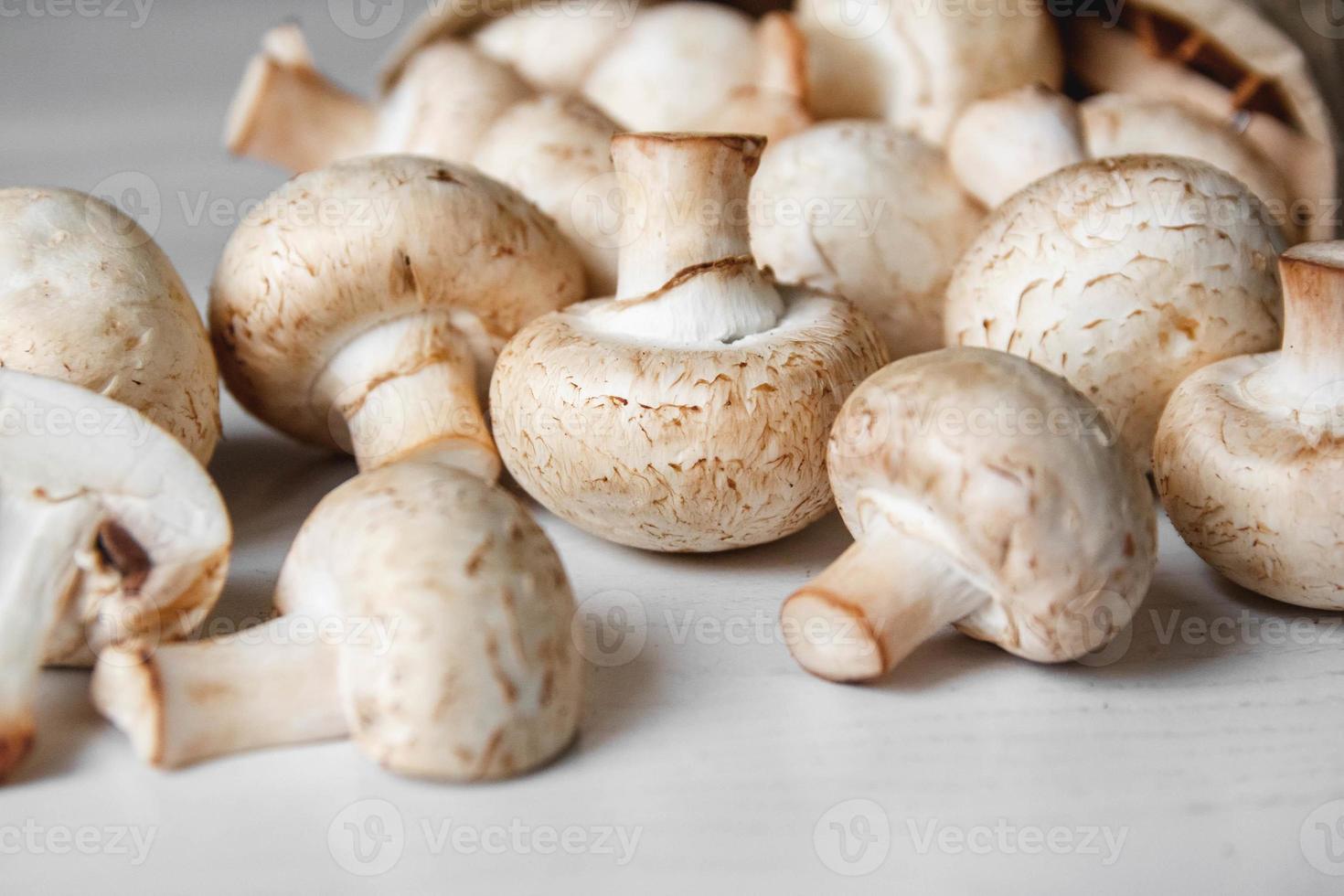 Champiñones champiñones en una bolsa de papel sobre una mesa de madera blanca foto