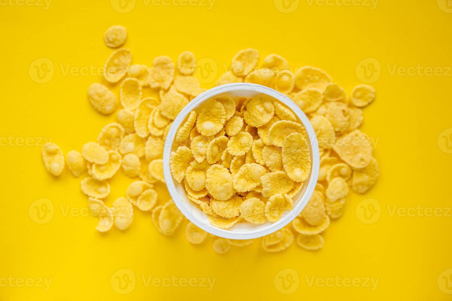 Cornflakes in white bowl on yellow background photo