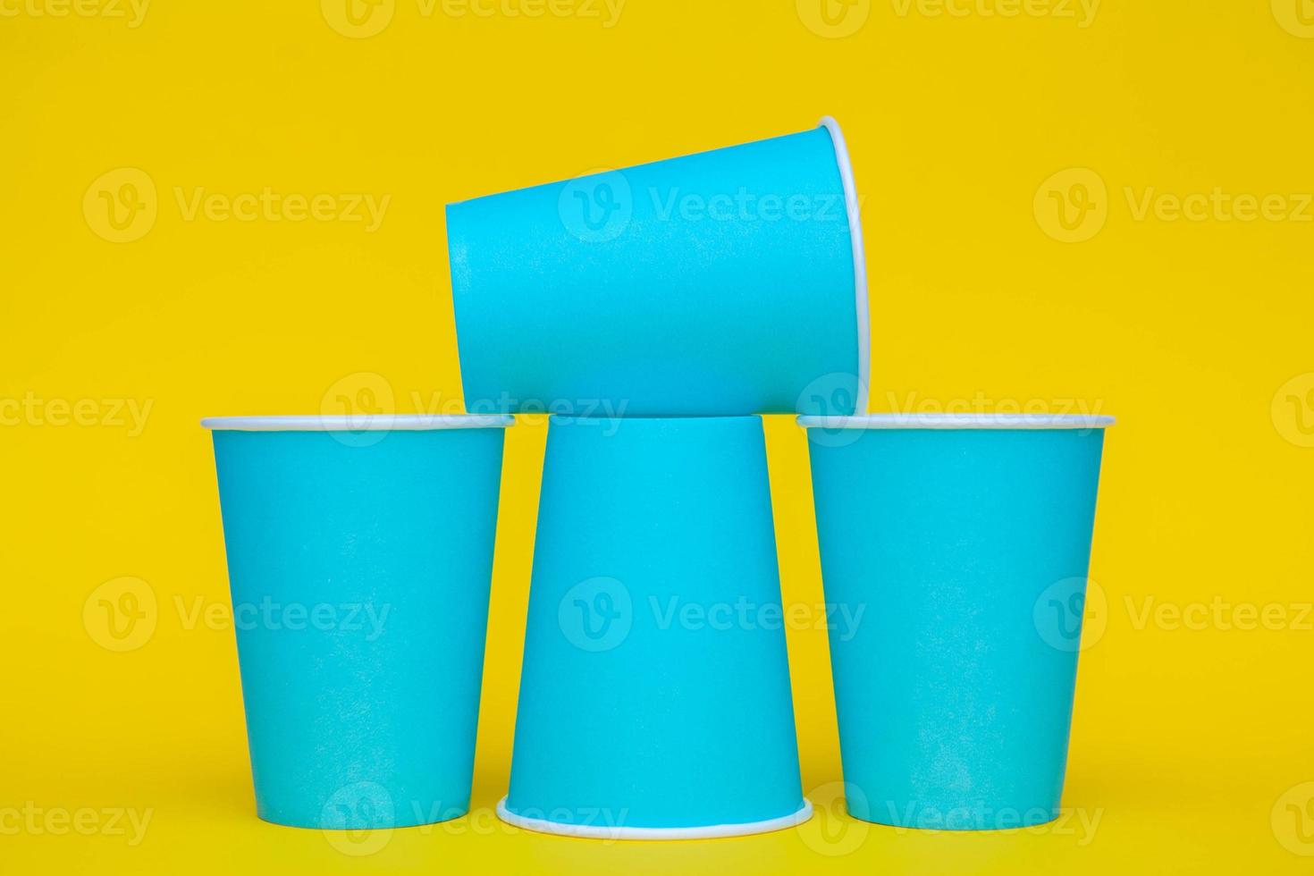 Pirámide de vasos desechables de papel azul sobre fondo amarillo foto