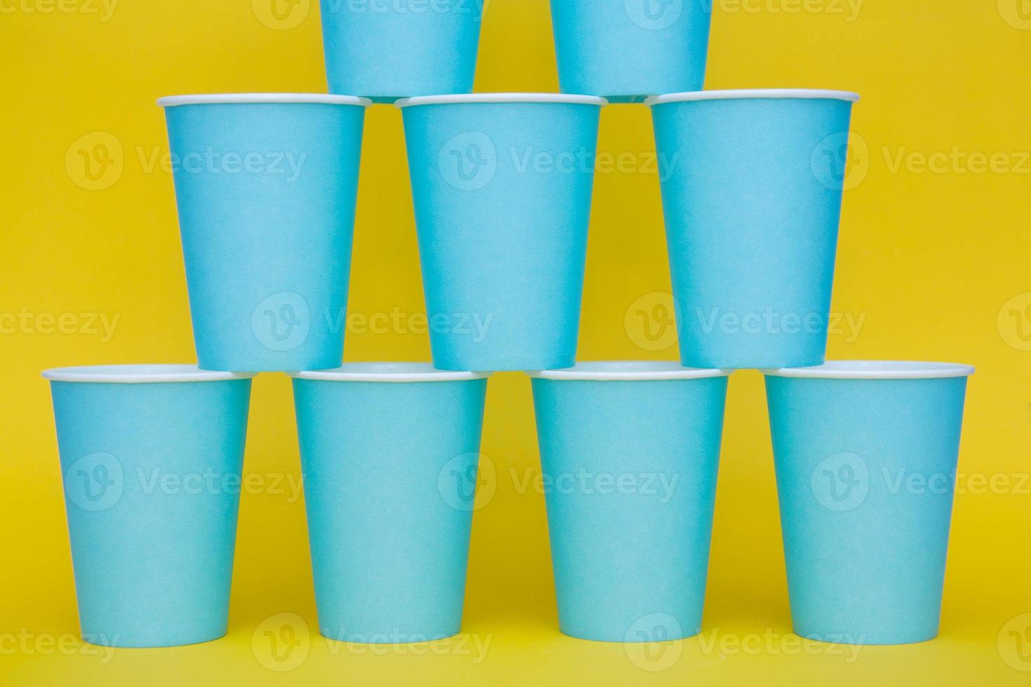 Pirámide de vasos desechables de papel azul sobre fondo amarillo foto