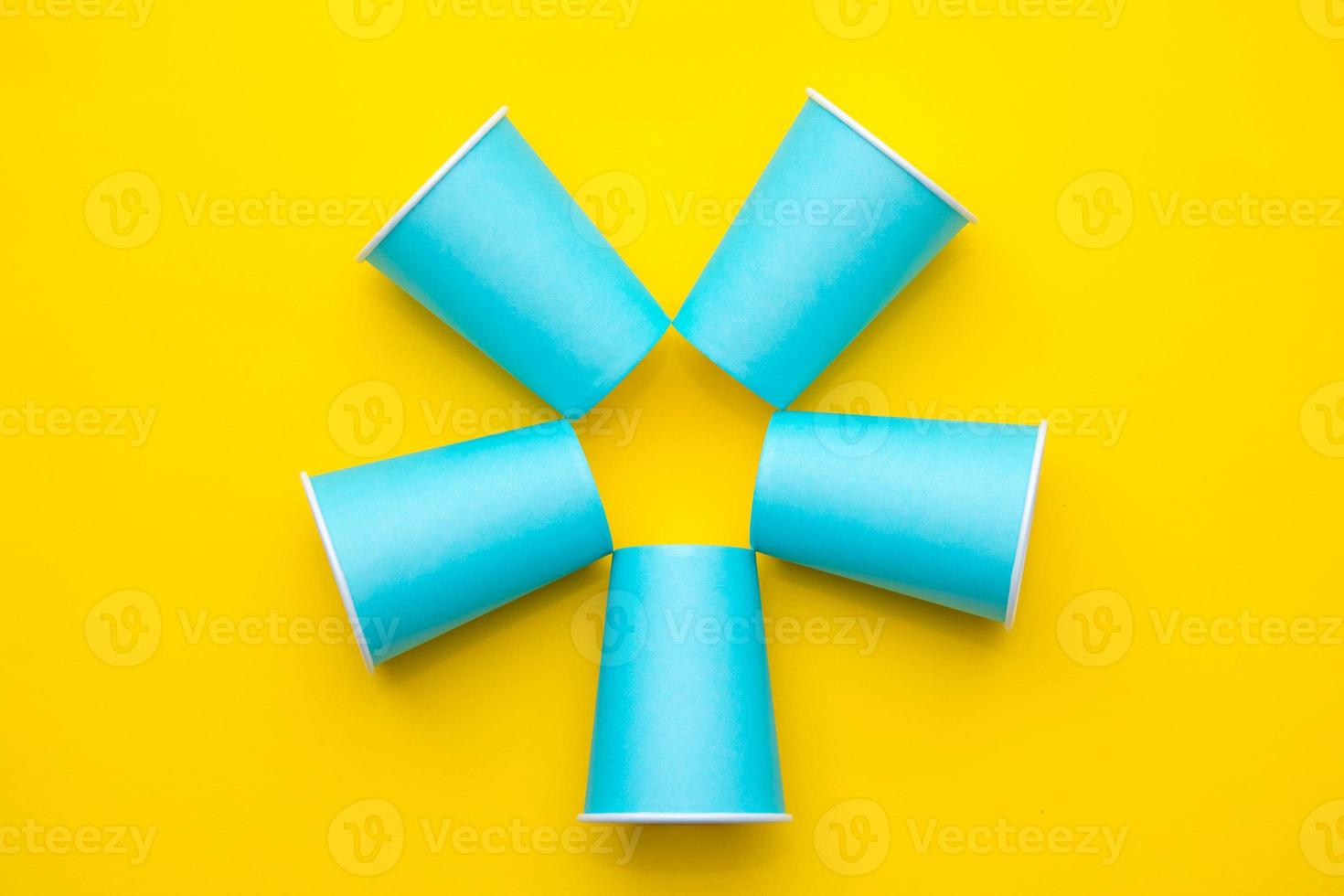 patrón de vasos desechables de papel azul sobre fondo amarillo. listo para la fiesta foto