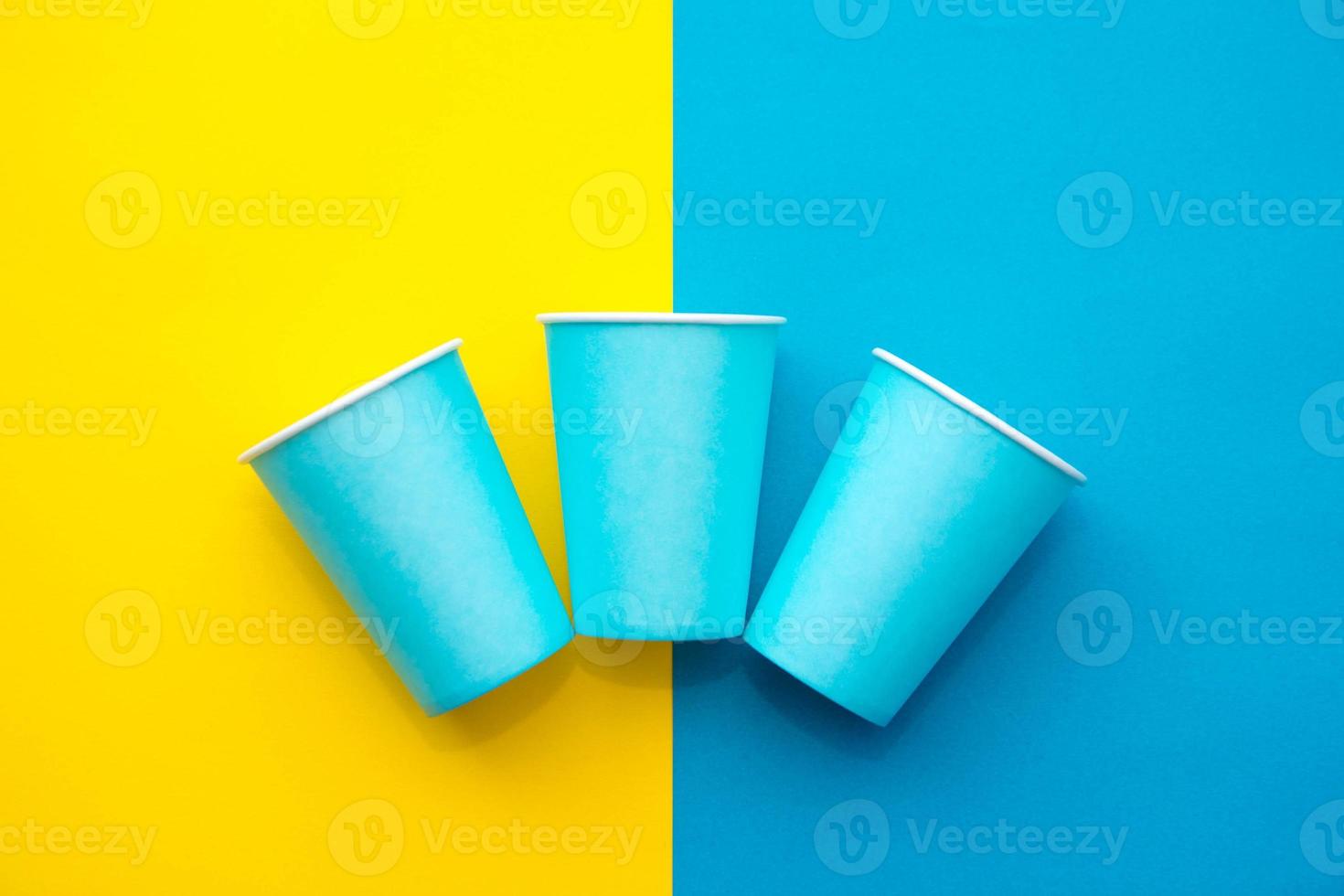 vasos desechables de papel azul fondo amarillo y azul foto